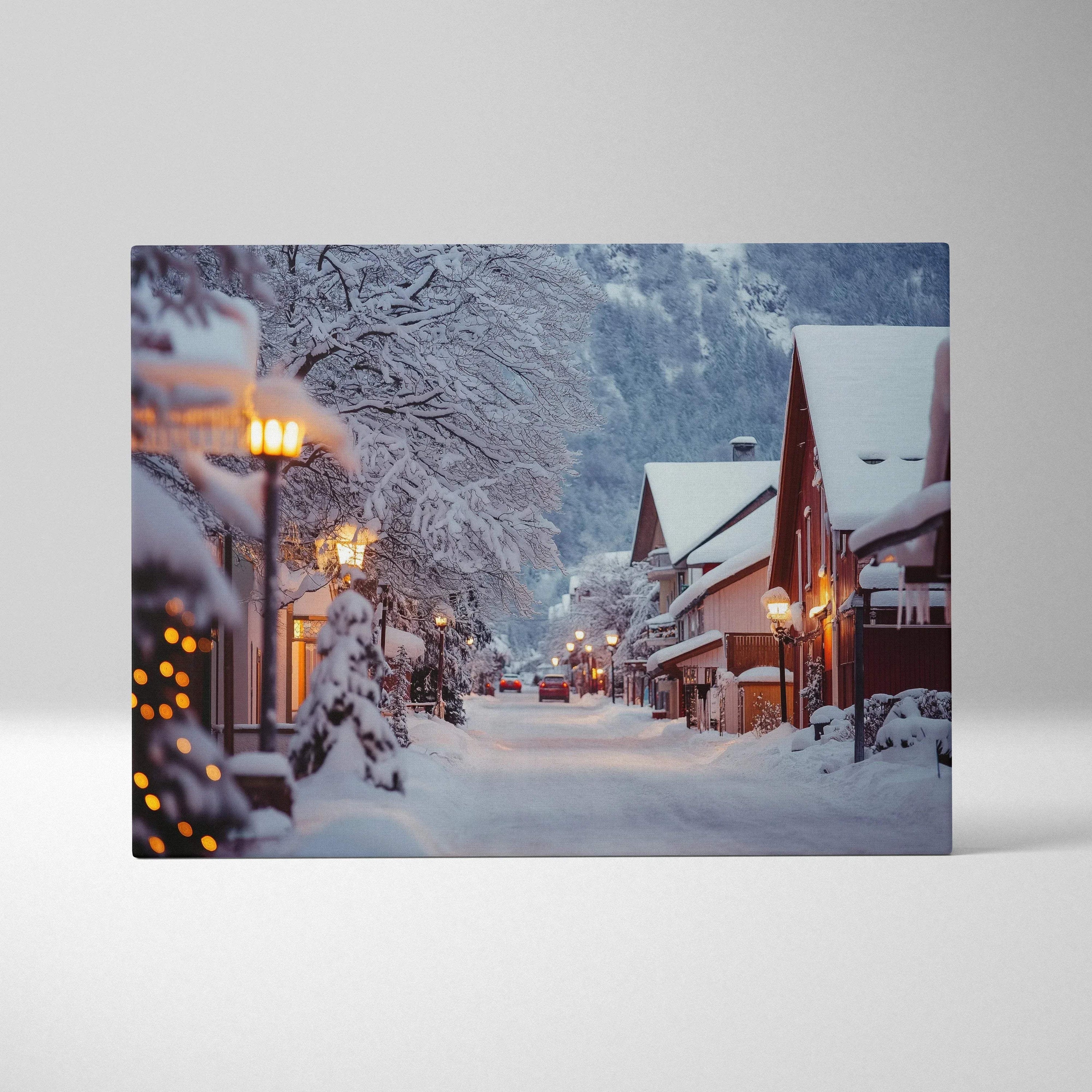 Canvas wall art featuring a snowy mountain town at dusk with warmly lit streetlamps and snow-covered rooftops.