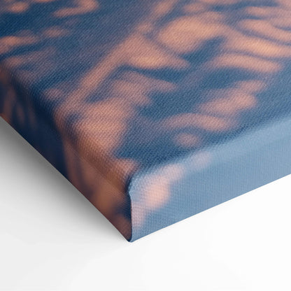 Close-up of textured canvas wall art with soft blue and warm orange tones from a snowy sunset scene.