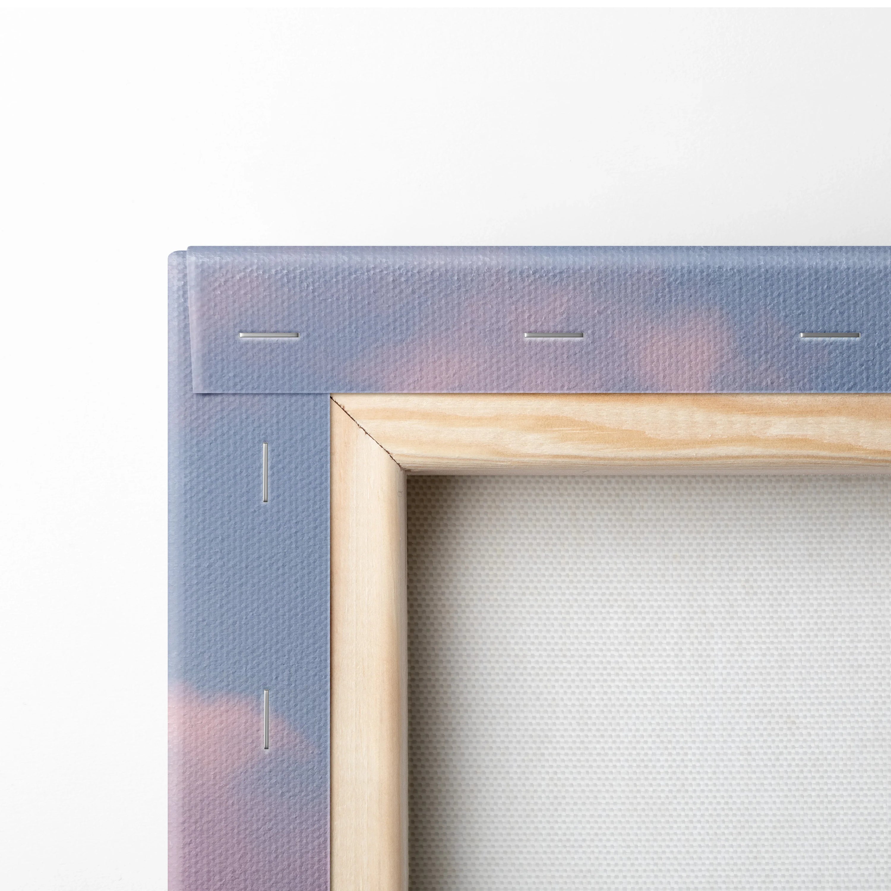 Close-up of canvas wall art stretched on wooden frame with faded pink and purple minimalist desert dunes decor.