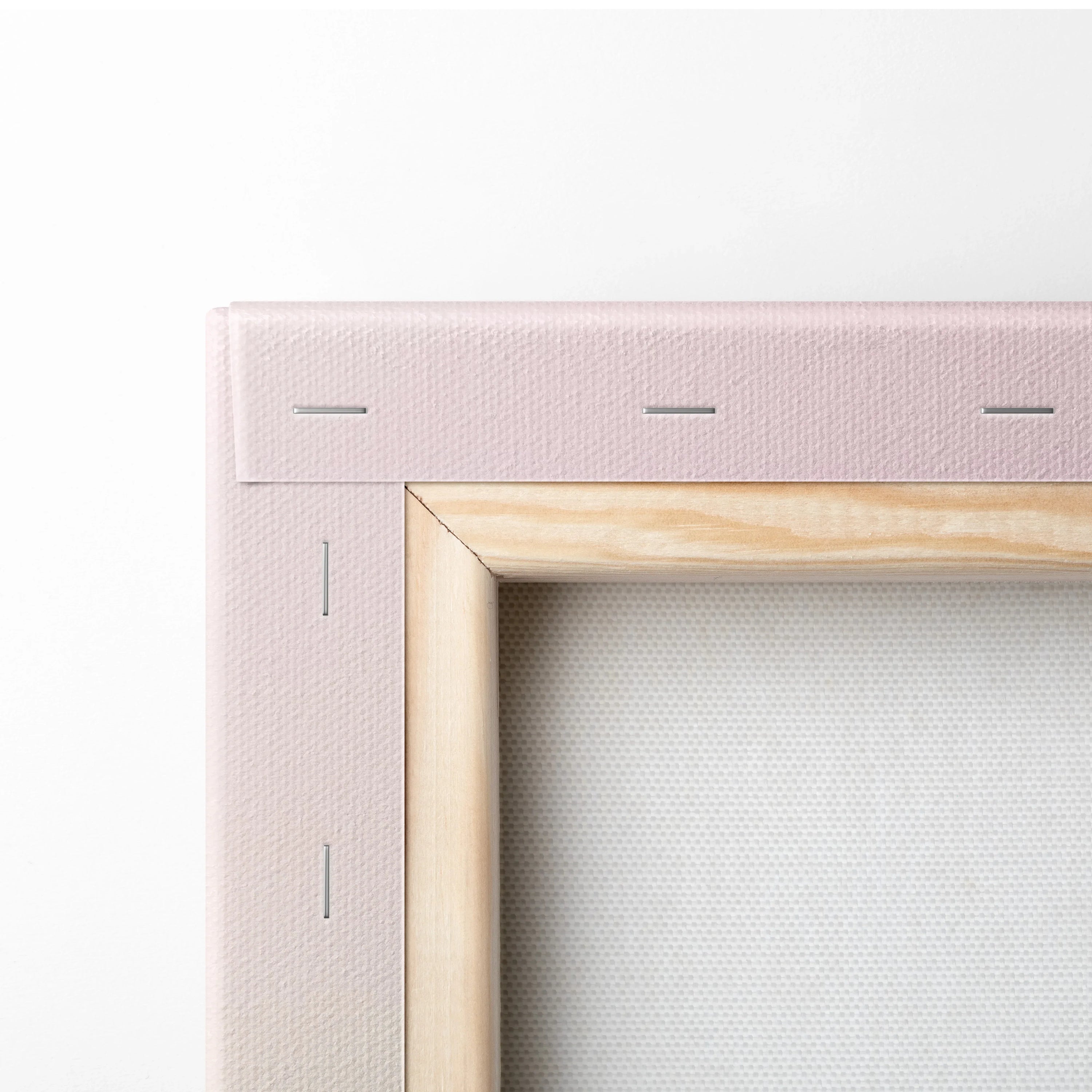 Close-up of canvas corner with light wood frame and pale pink fabric backing, wall art decor detail.