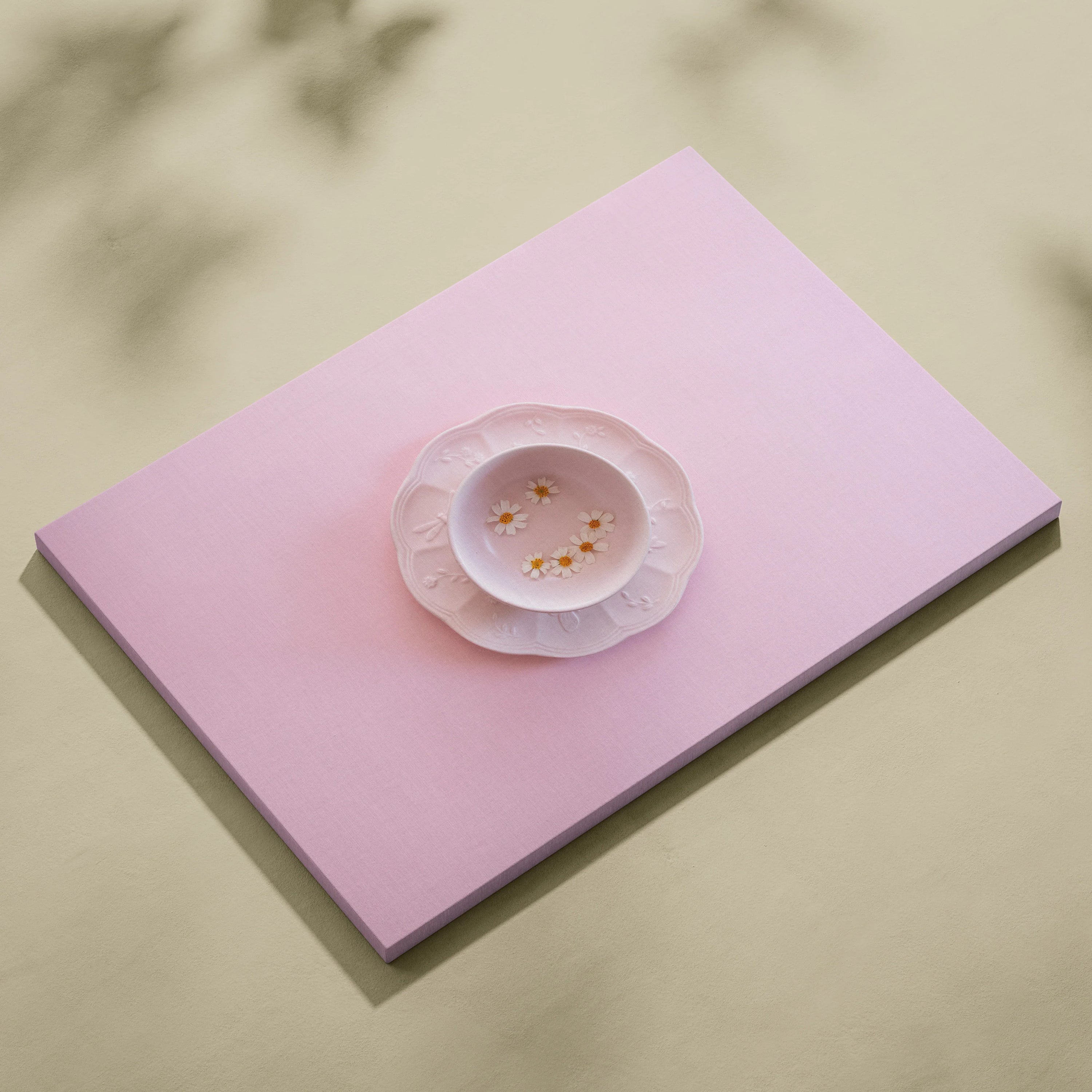 Minimalist pink canvas wall art featuring a delicate white plate with small yellow flowers, modern decor piece.