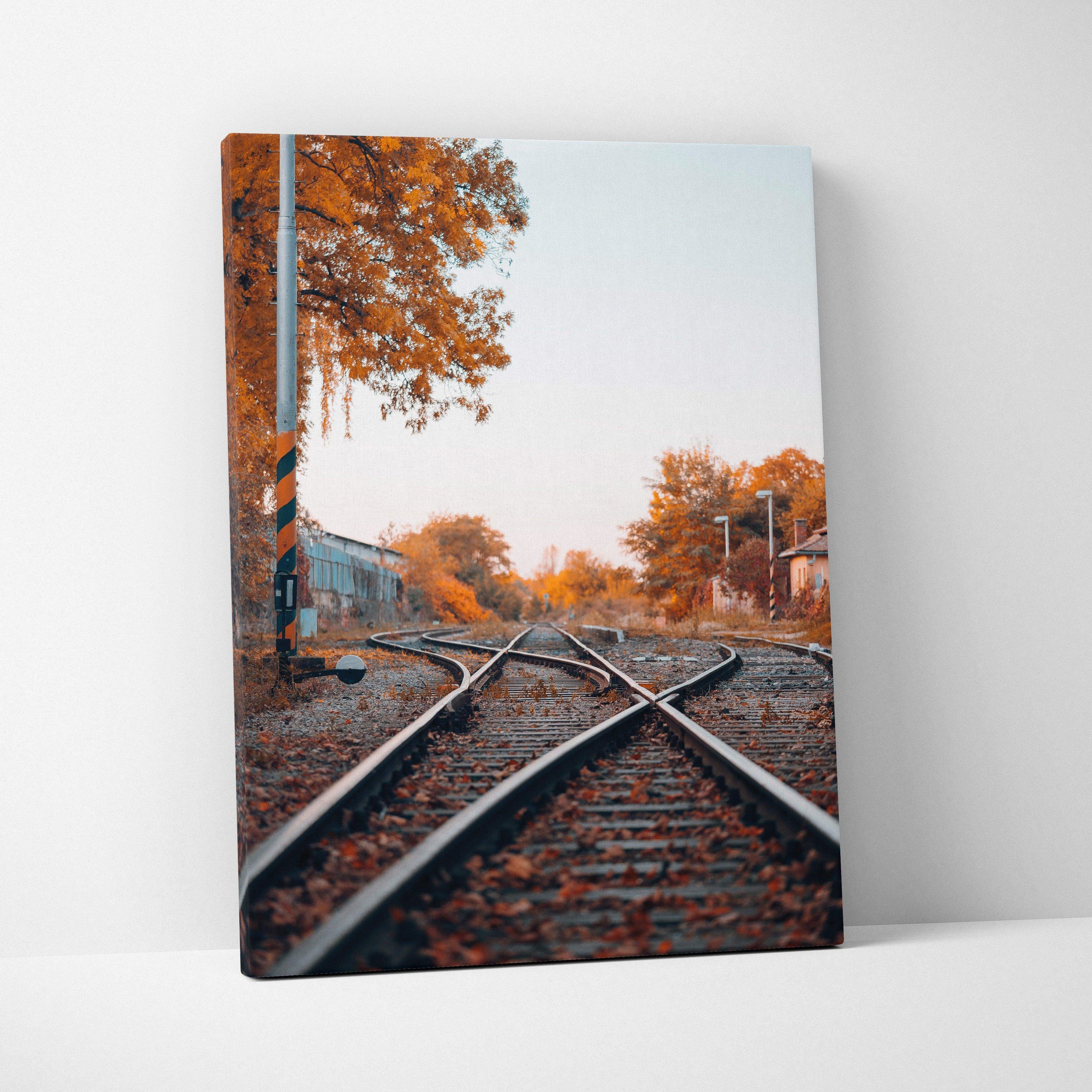 Vertical canvas wall art featuring autumn trees and railroad tracks in warm tones.