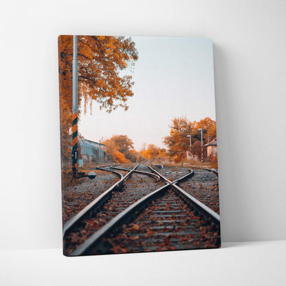 Vertical canvas wall art featuring autumn trees and railroad tracks in warm tones.