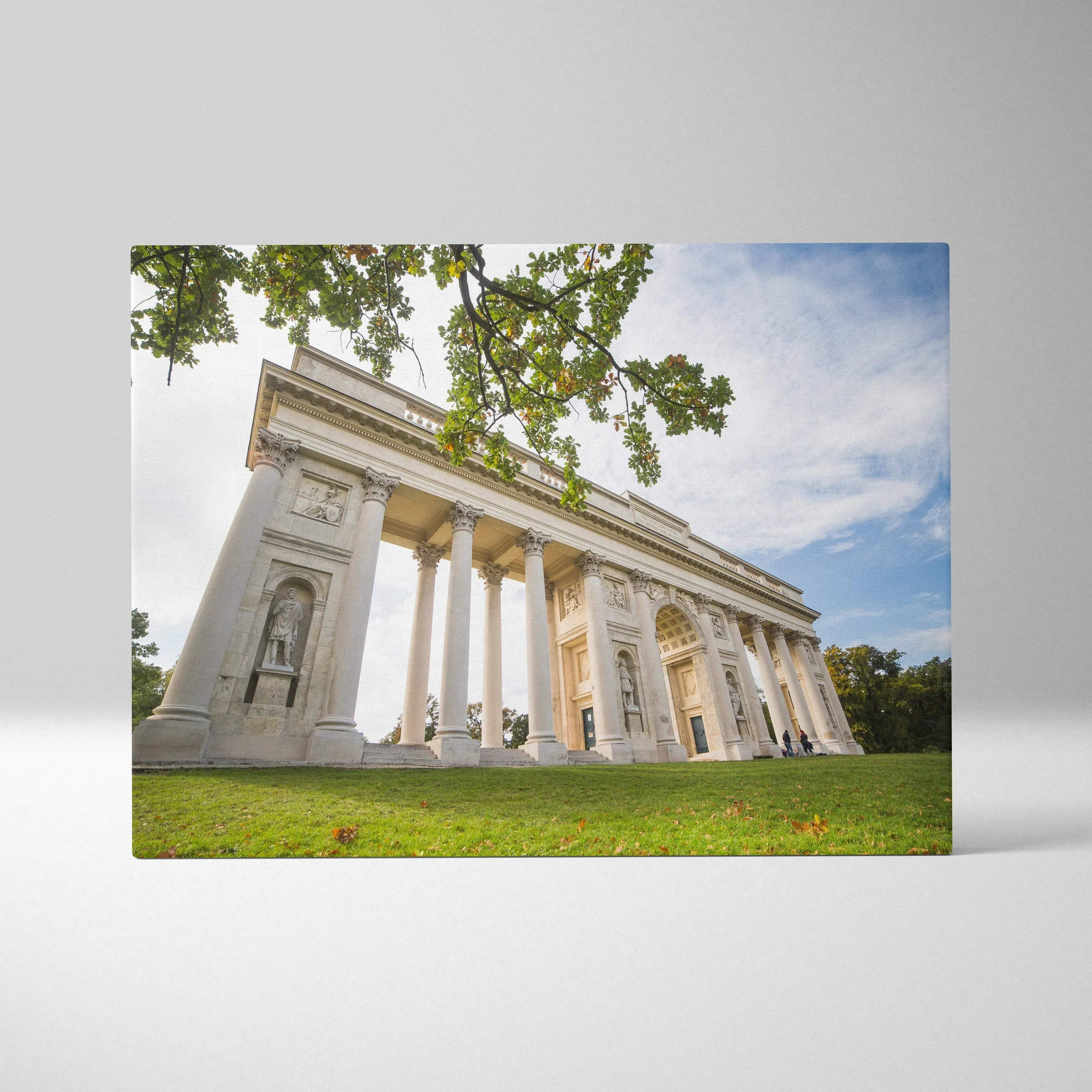 White classical building with columns printed on canvas wall art, set against blue sky and green grass background.