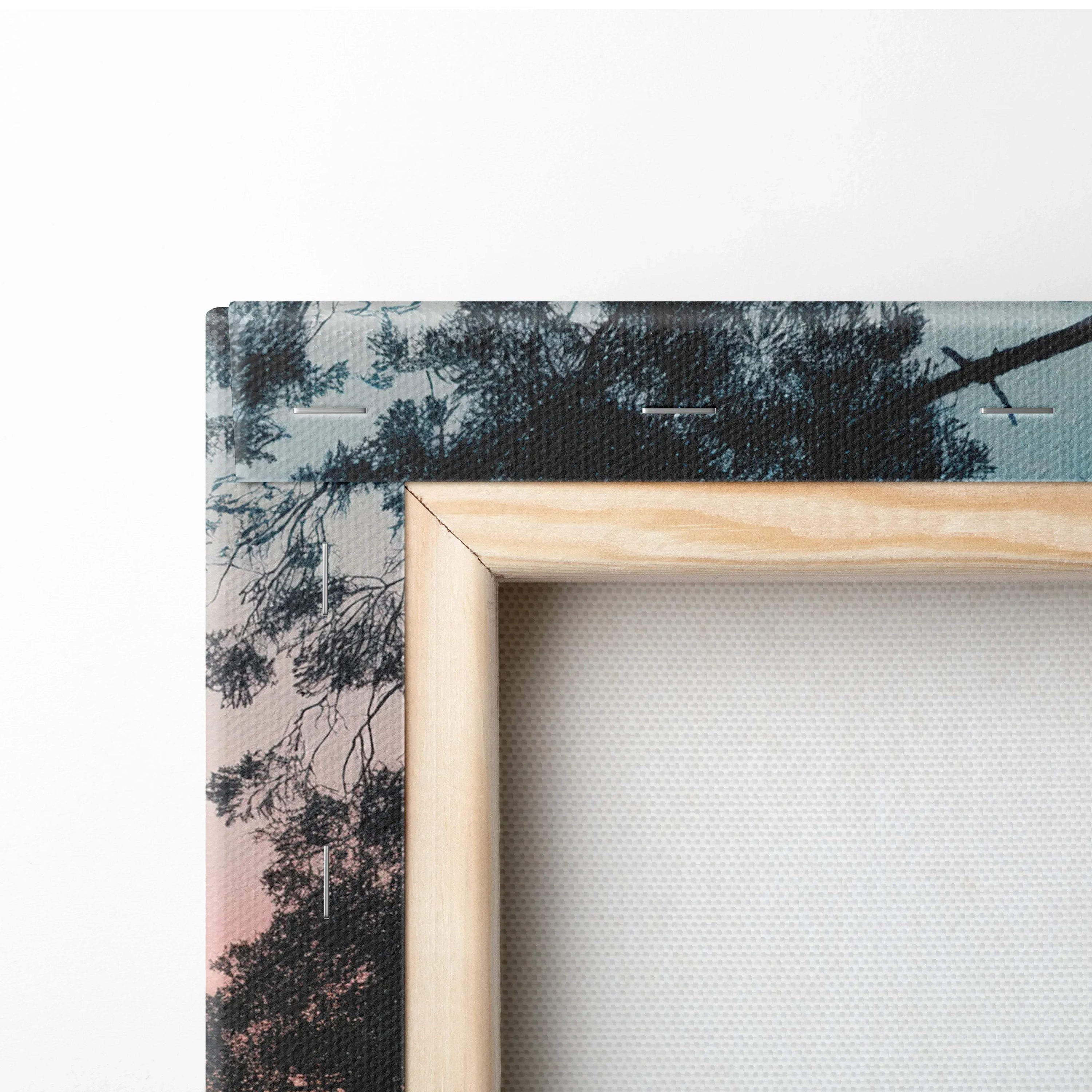 Close-up of forest sunset canvas wall art corner with natural wood frame and vibrant nature scene decor.