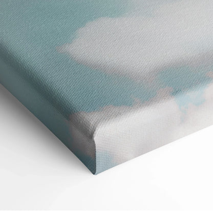 Close-up of canvas wall art showing soft blue sky and white cloud shapes with minimalist, smooth texture and wrapped edges.