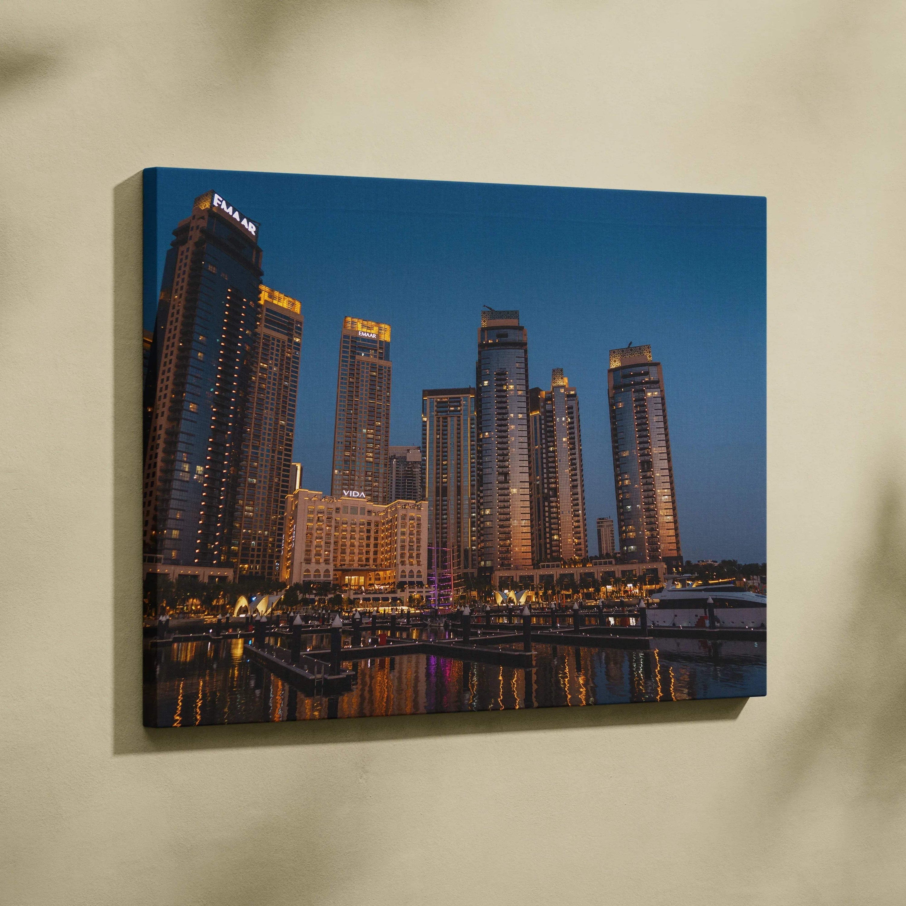 Canvas wall art featuring a nighttime city skyline with illuminated skyscrapers and reflective water.