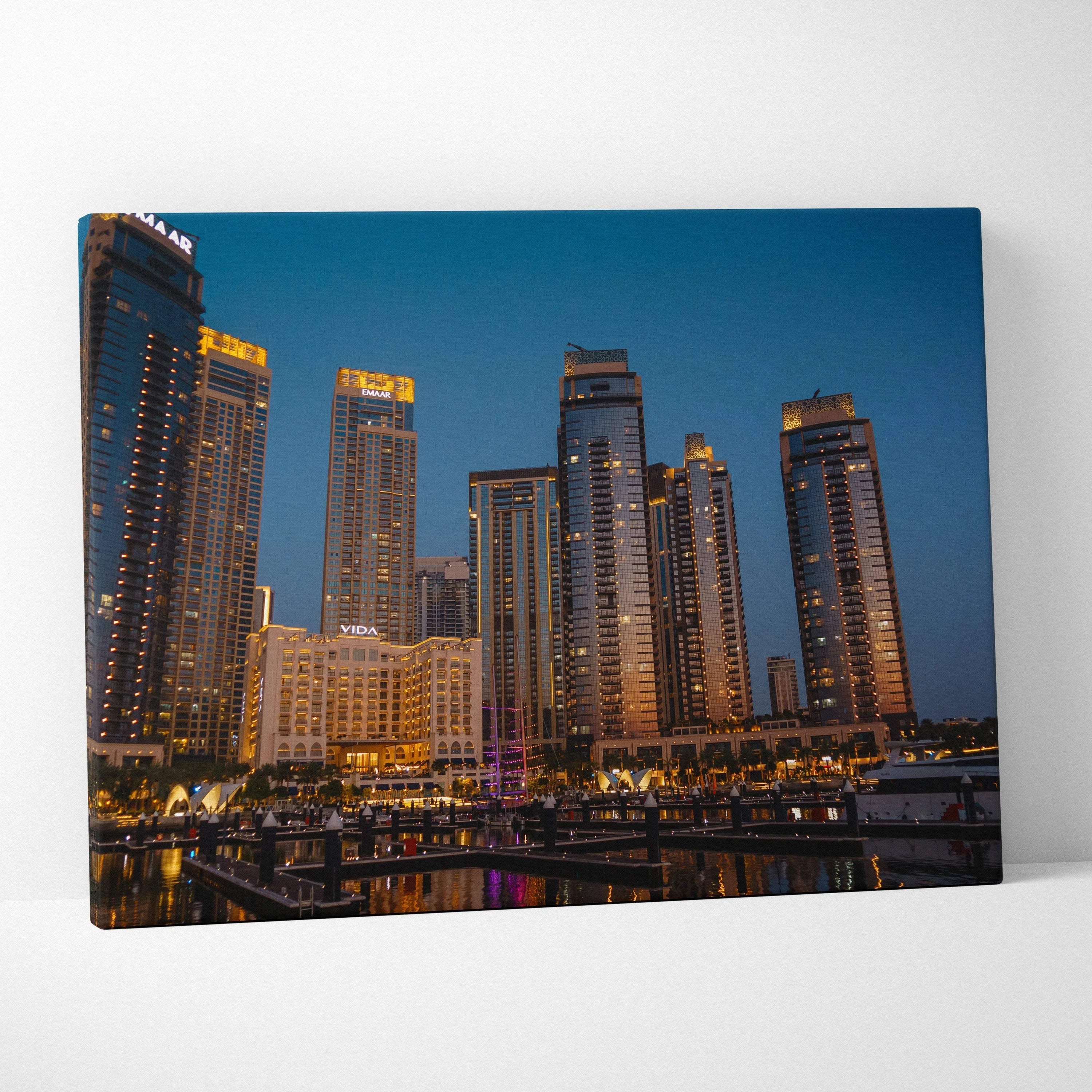 Canvas wall art featuring a nighttime city skyline with illuminated modern skyscrapers against a deep blue sky.