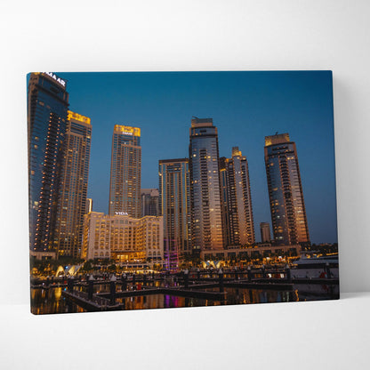 Canvas wall art featuring a nighttime city skyline with illuminated modern skyscrapers against a deep blue sky.