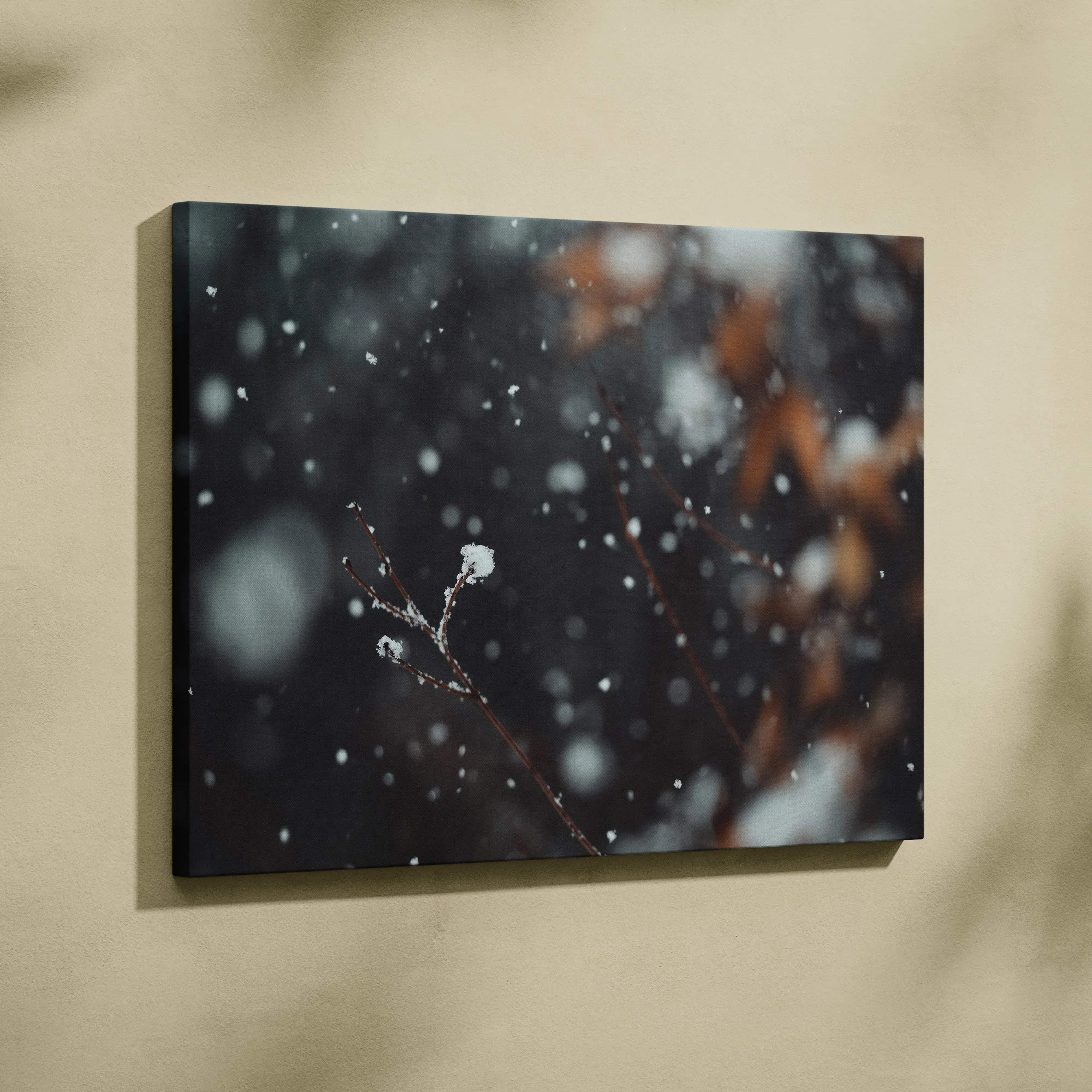 Black canvas wall art featuring a delicate twig with snowflakes in moody blue winter tones against blurred backdrop