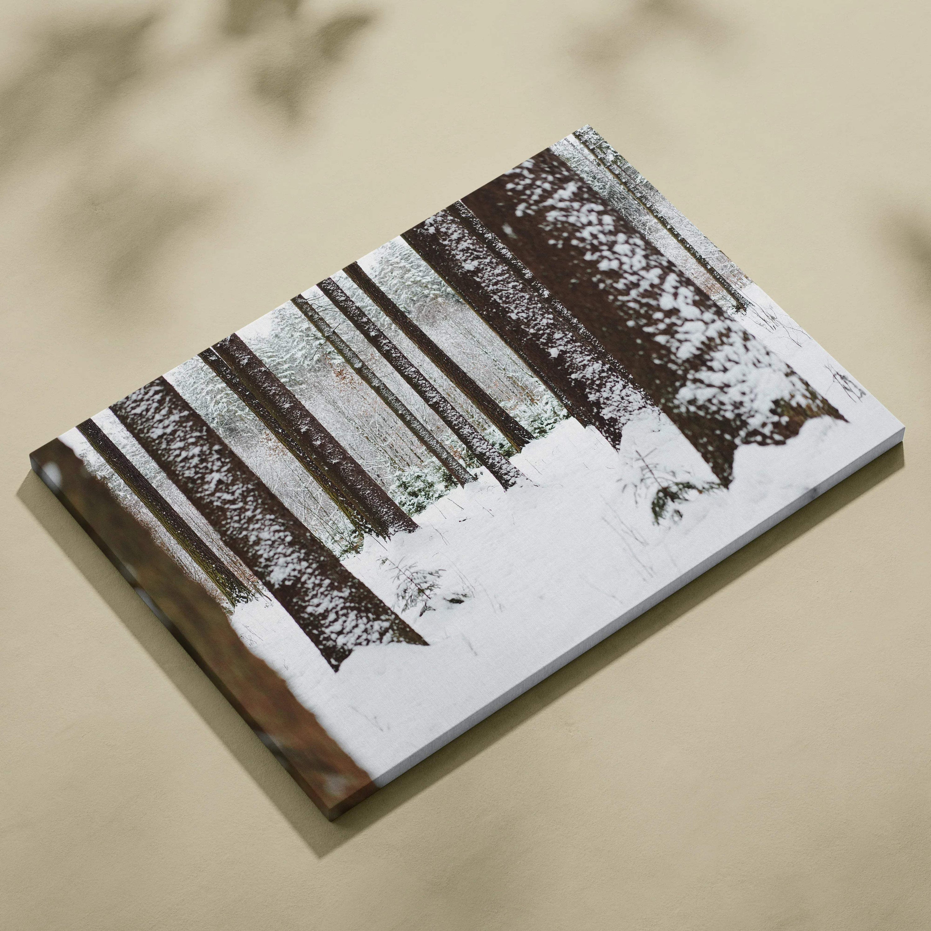 Canvas wall art depicting a snowy forest scene with tall, dark tree trunks and white snow covering the ground and branches.