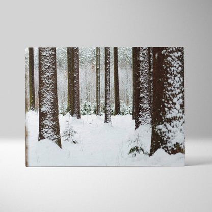 Canvas wall art featuring a snowy forest with tall pine trees covered in fresh white snow and a soft, muted color palette.