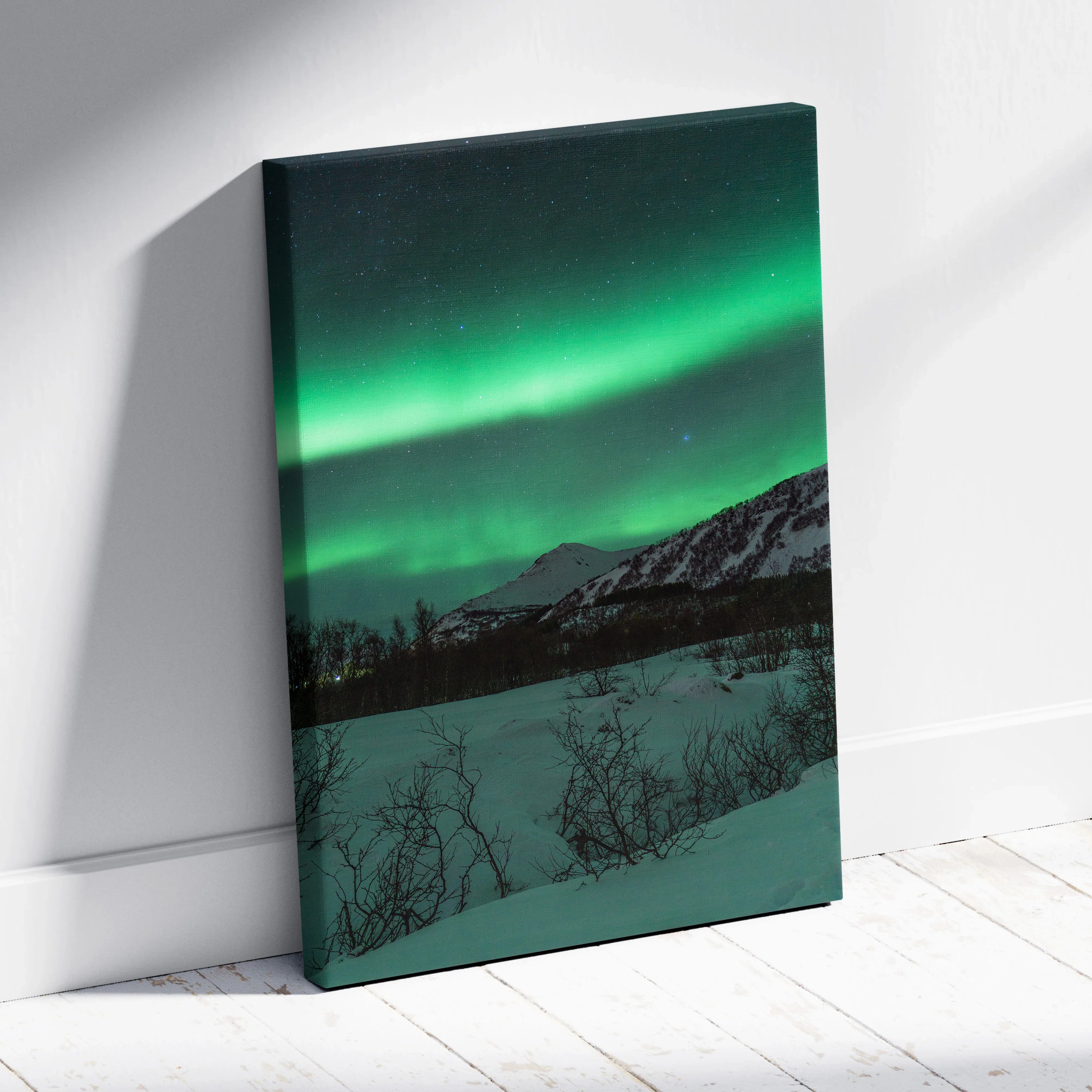 Canvas wall art featuring vibrant green northern lights over snow-covered mountains and a dark forest foreground.
