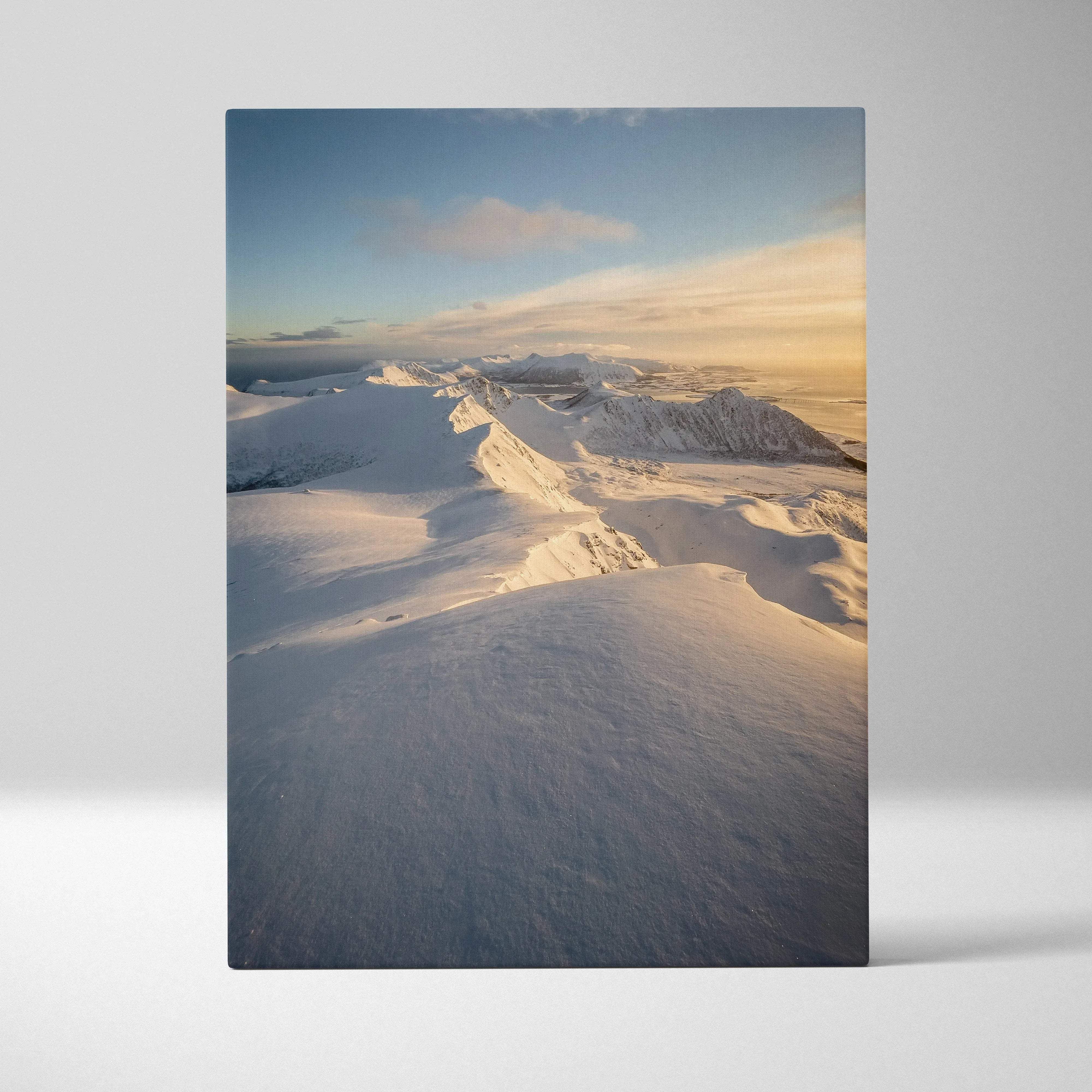 Serene snowy norwegian mountains sunrise canvas wall art featuring golden hour light on snow-covered peaks against blue sky