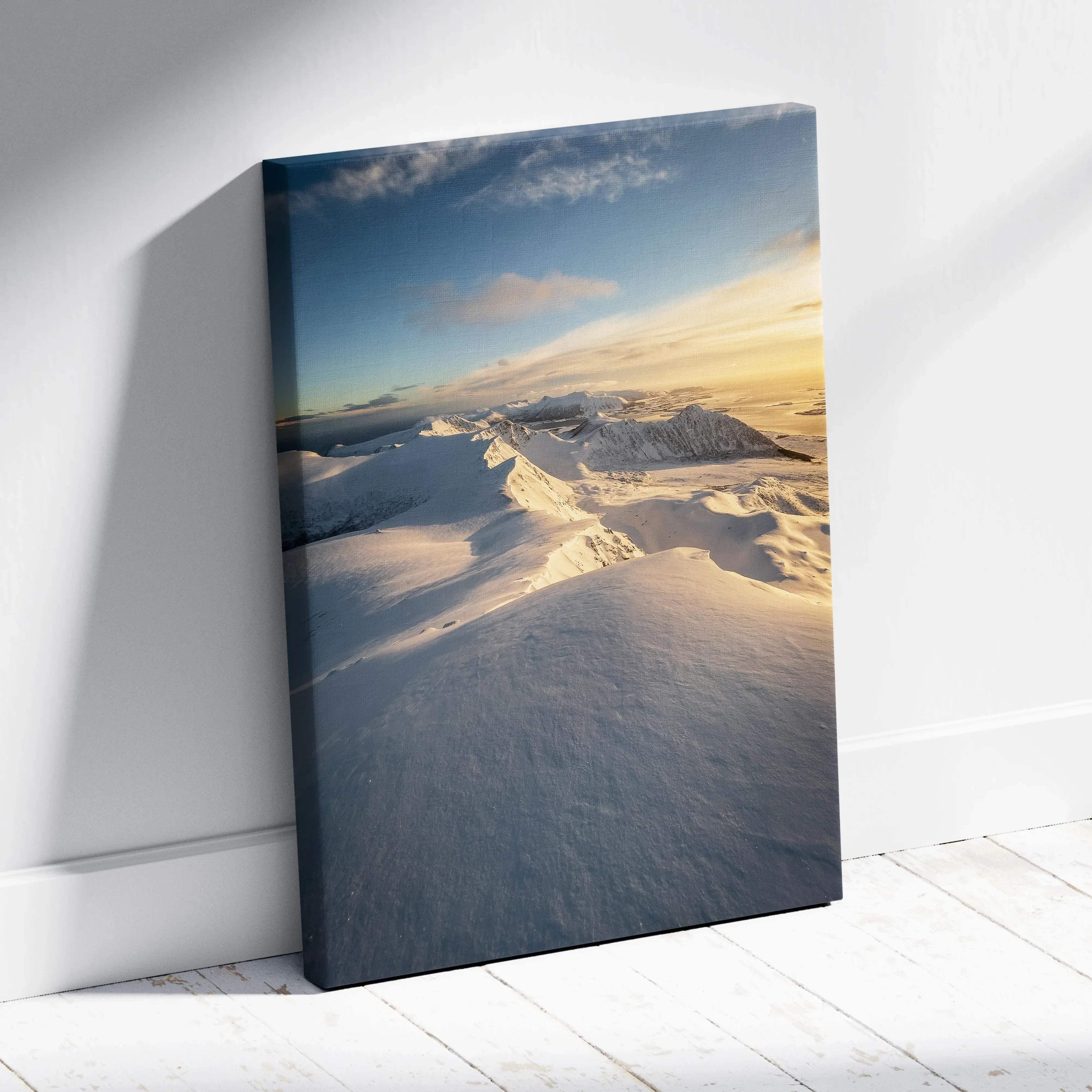 Rectangular canvas print of serene snowy norwegian mountains at sunrise with golden light and blue sky clouds