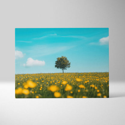 Canvas wall art featuring a solitary tree in a blooming yellow floral meadow under a bright blue sky.