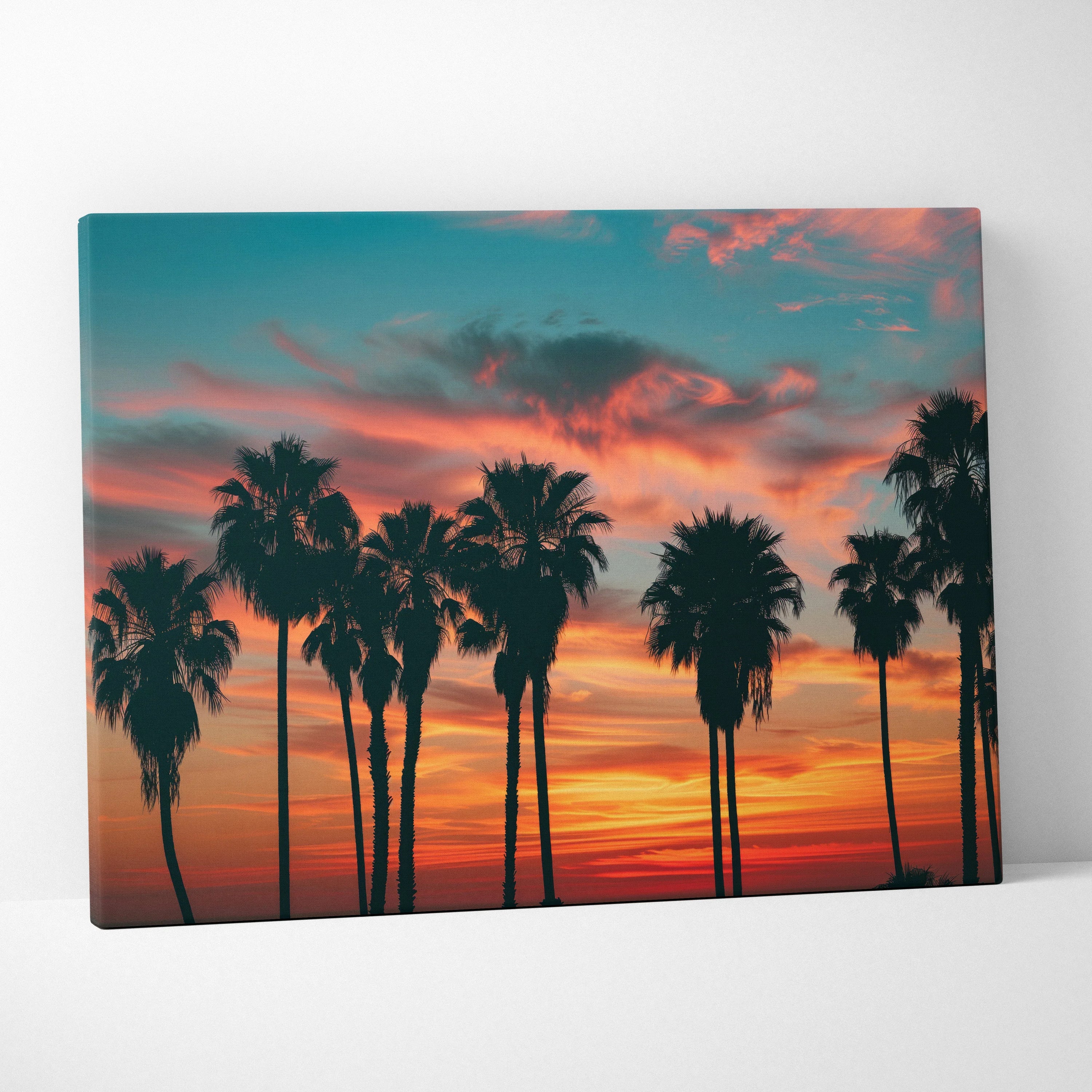 Canvas wall art featuring black palm tree silhouettes against a vibrant tropical sunset sky with orange, pink, and blue hues.