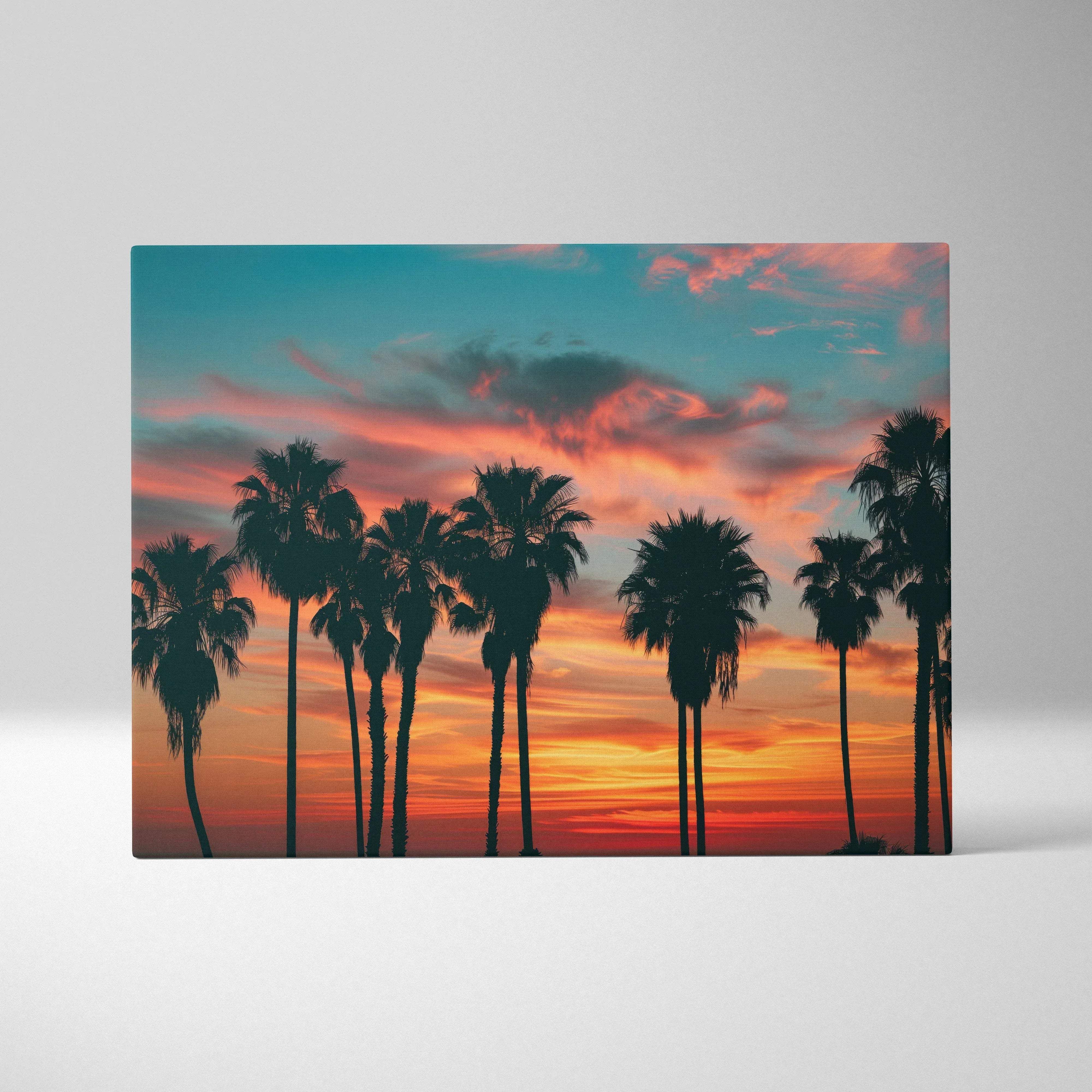 A rectangular canvas print of silhouetted palm trees with vibrant orange pink and teal sunset sky for home decor
