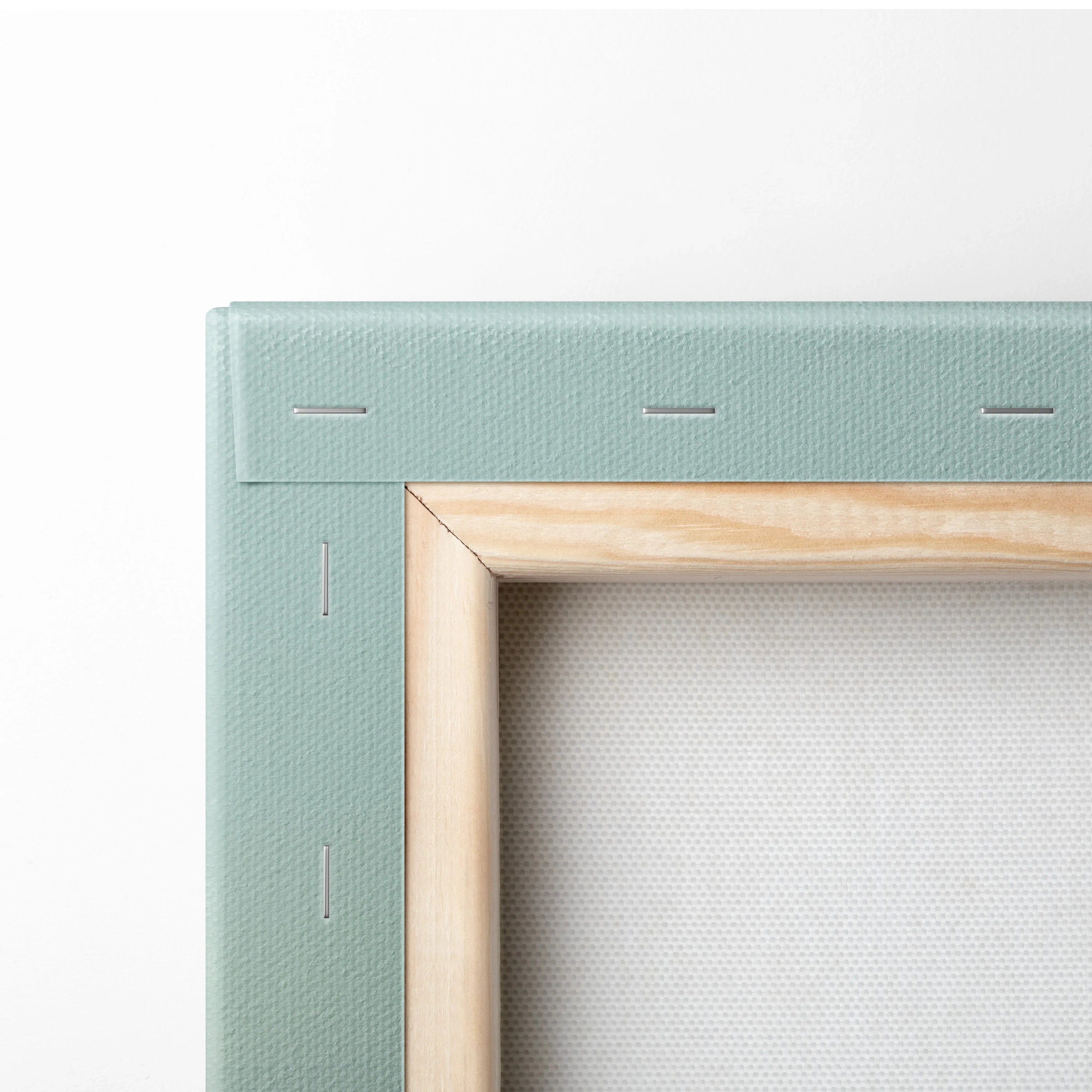 Close-up of canvas corner with light green fabric stretched over wooden frame, showcasing texture and stapled edges.