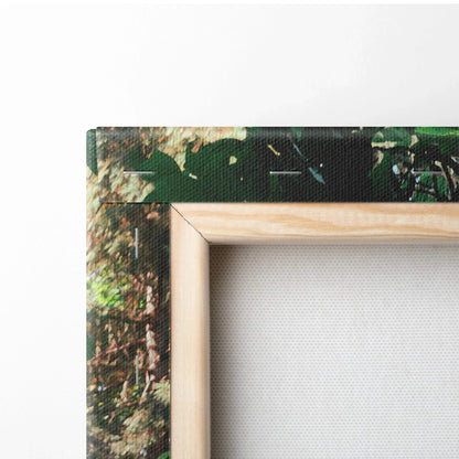 Close-up of wood-framed vertical canvas wall art corner with green foliage print and museum-quality texture.