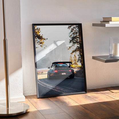 Framed RWB Porsche 911 poster leaning on floor with forest wall art background in natural light.