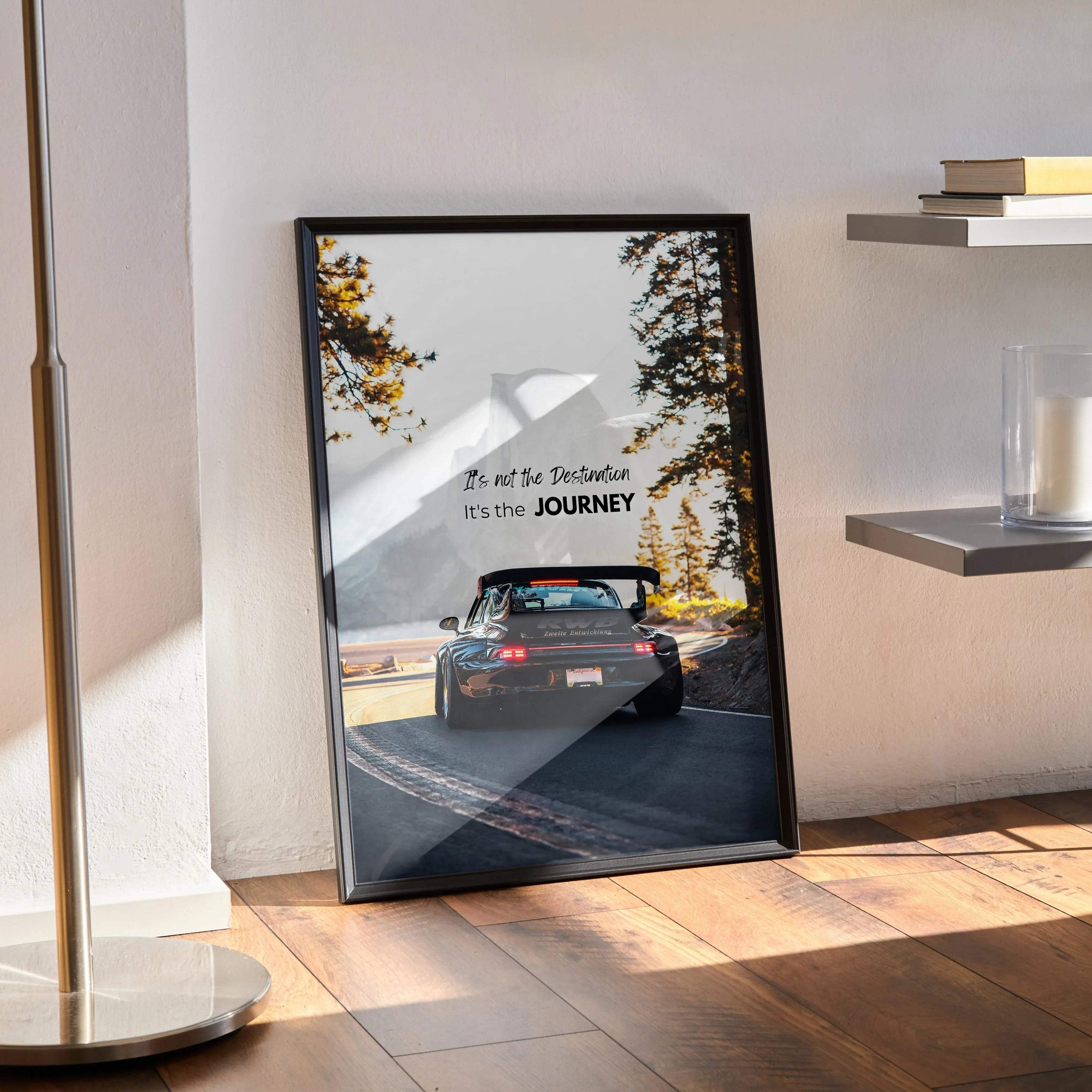 Black-framed motivational poster featuring a dark blue porsche 911 on a winding road with inspiring white text