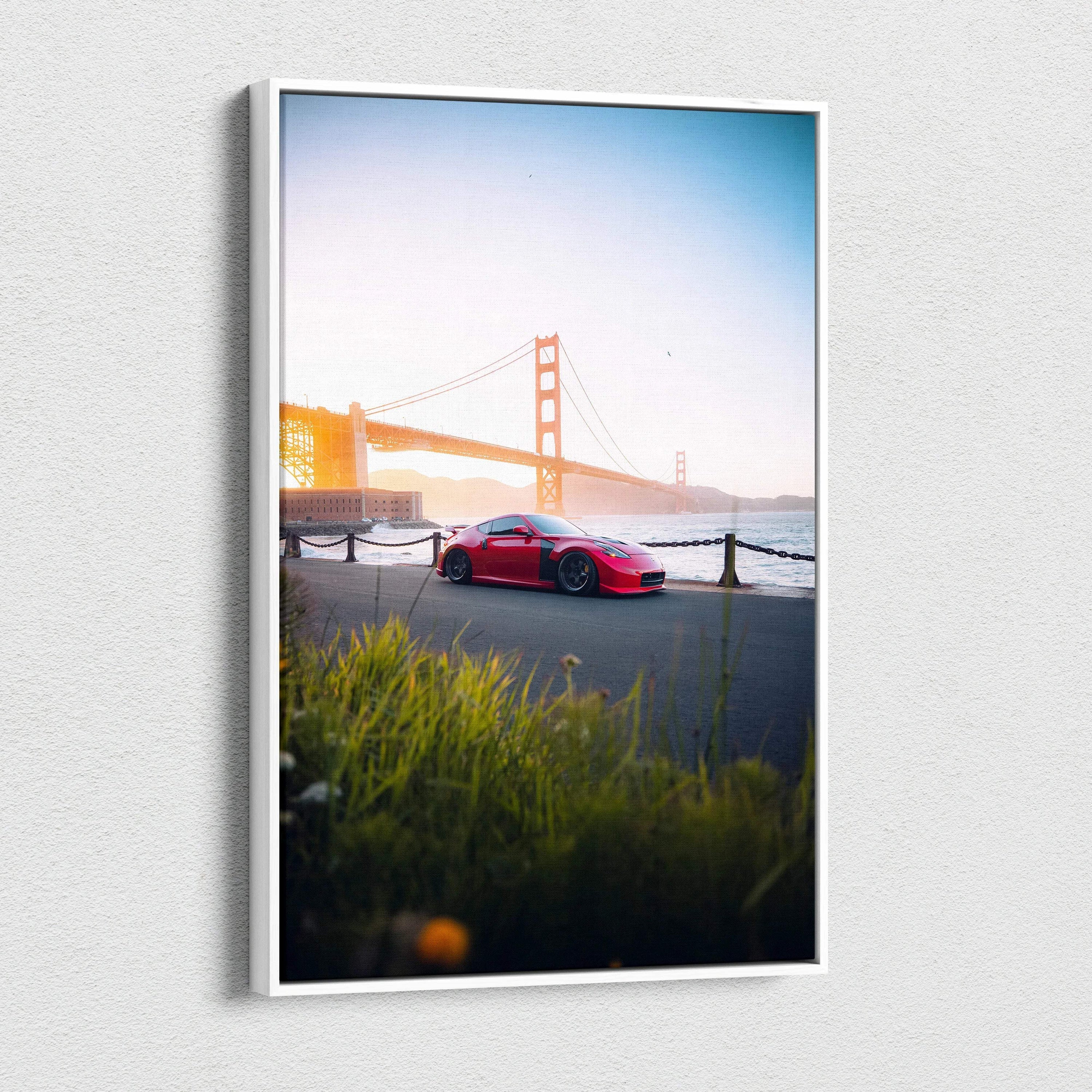 Vertical canvas art of red Nissan 370z parked by water with Golden Gate Bridge in background.