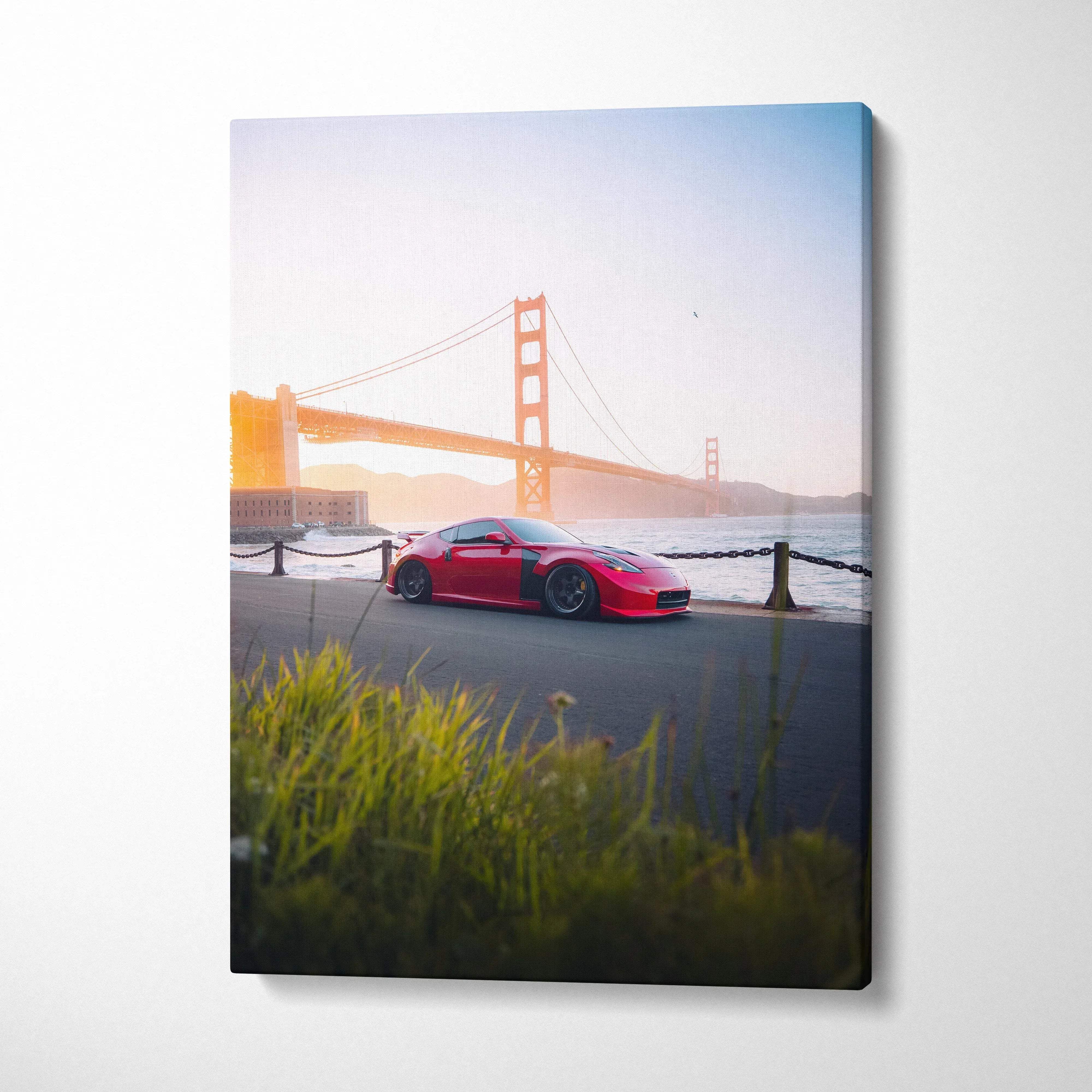 Vertical canvas art featuring a red Nissan 370z parked by the Golden Gate Bridge at sunset, wall art with vivid colors.