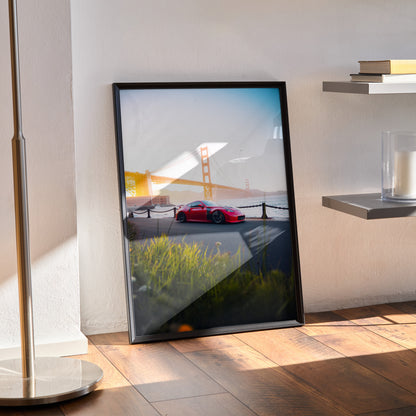 Nissan 370z poster wall art with red car and Golden Gate Bridge at sunset in black frame.