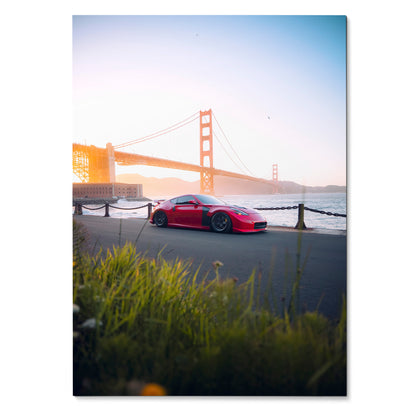 Nissan 370z red sports car parked by waterfront with Golden Gate Bridge at sunset poster wall art.