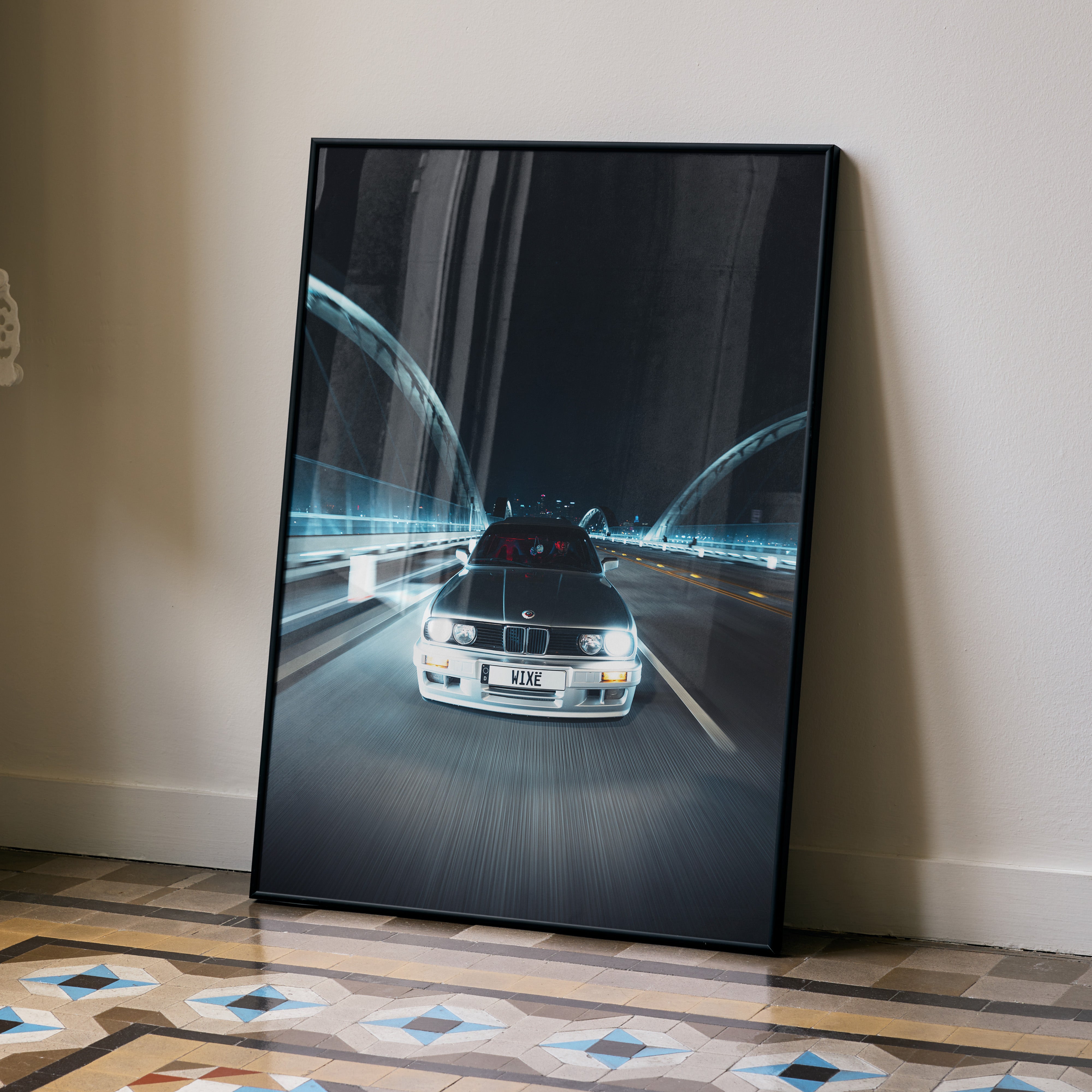 BMW E30 driving on a lit highway at night poster wall art in black frame.