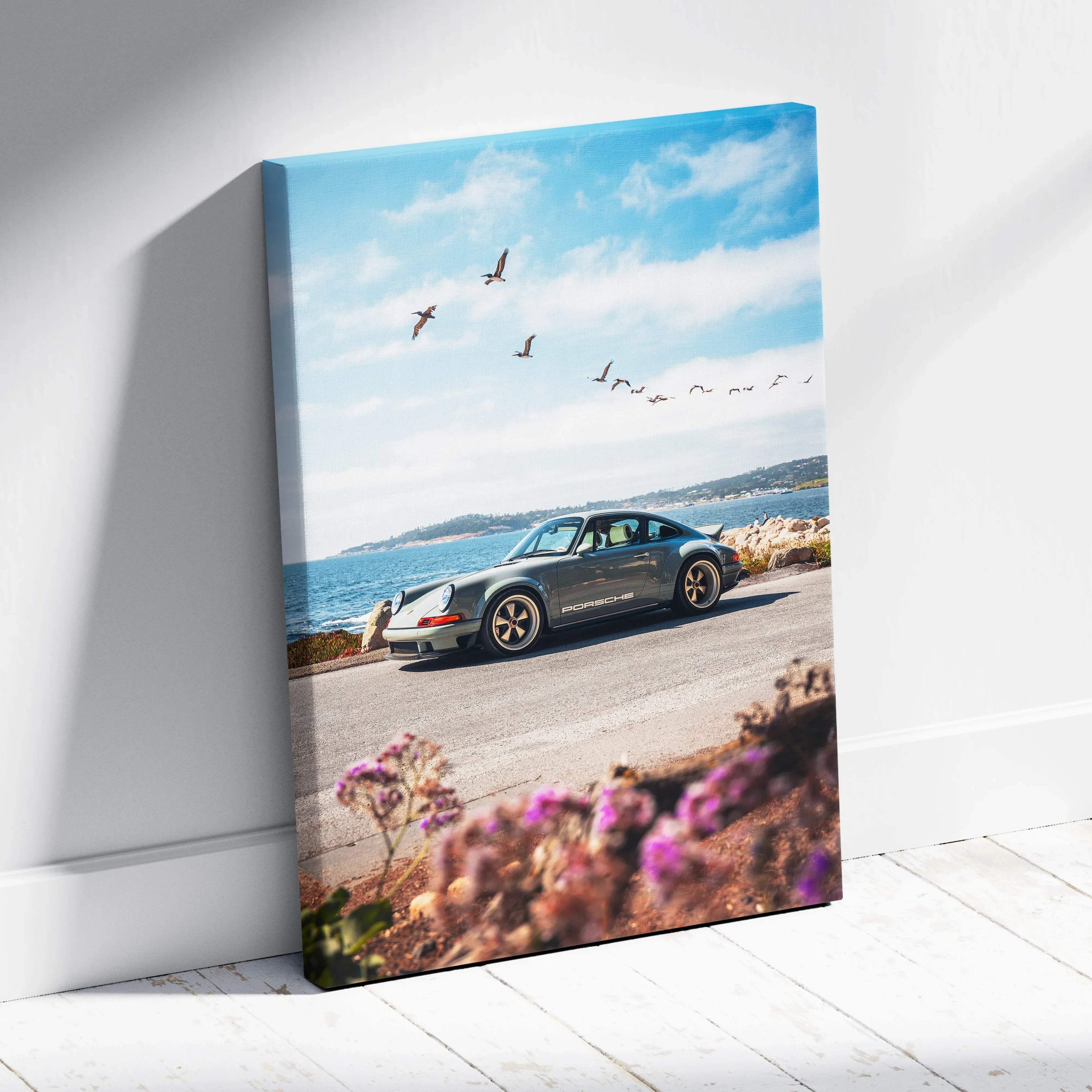 Canvas wall art featuring a vertical portrait of a gray porsche 911 with gold rims and coastal ocean blue calm scenery