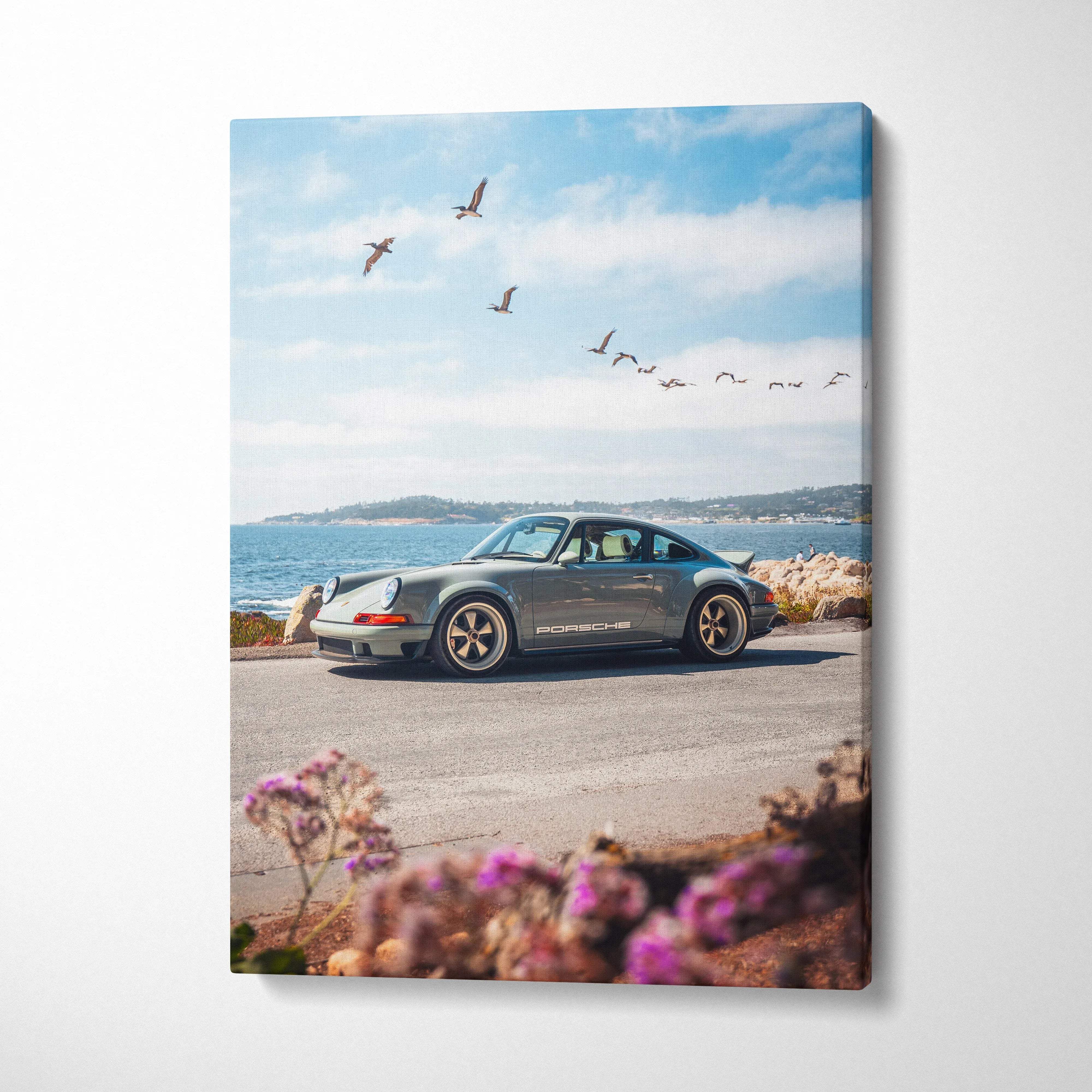 Porsche 911 classic car against ocean backdrop on vertical canvas wall art with coastal scenery and flowers.