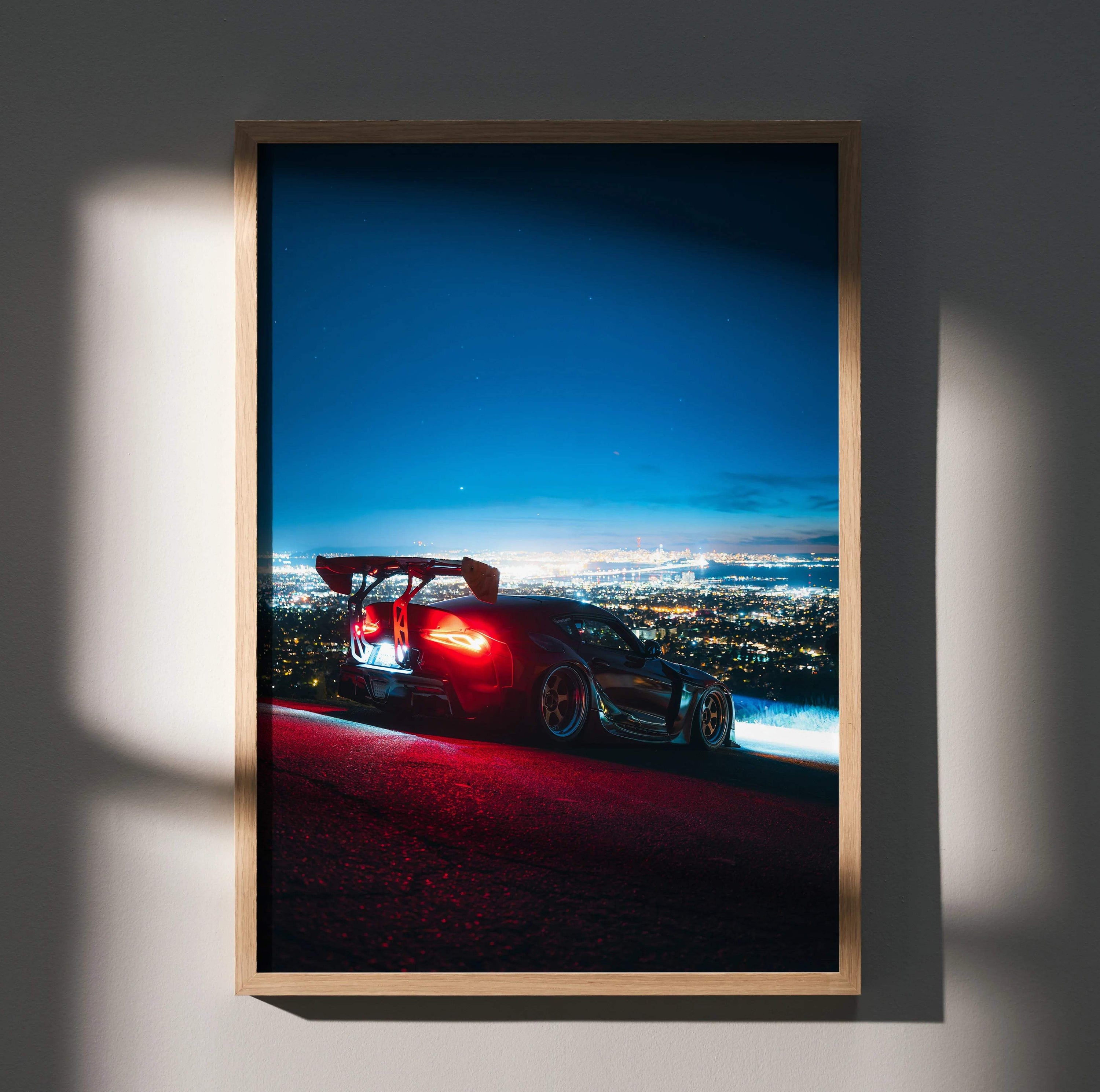 Toyota Supra Mk5 parked on hilltop at dusk with city lights below, poster wall art in wooden frame.