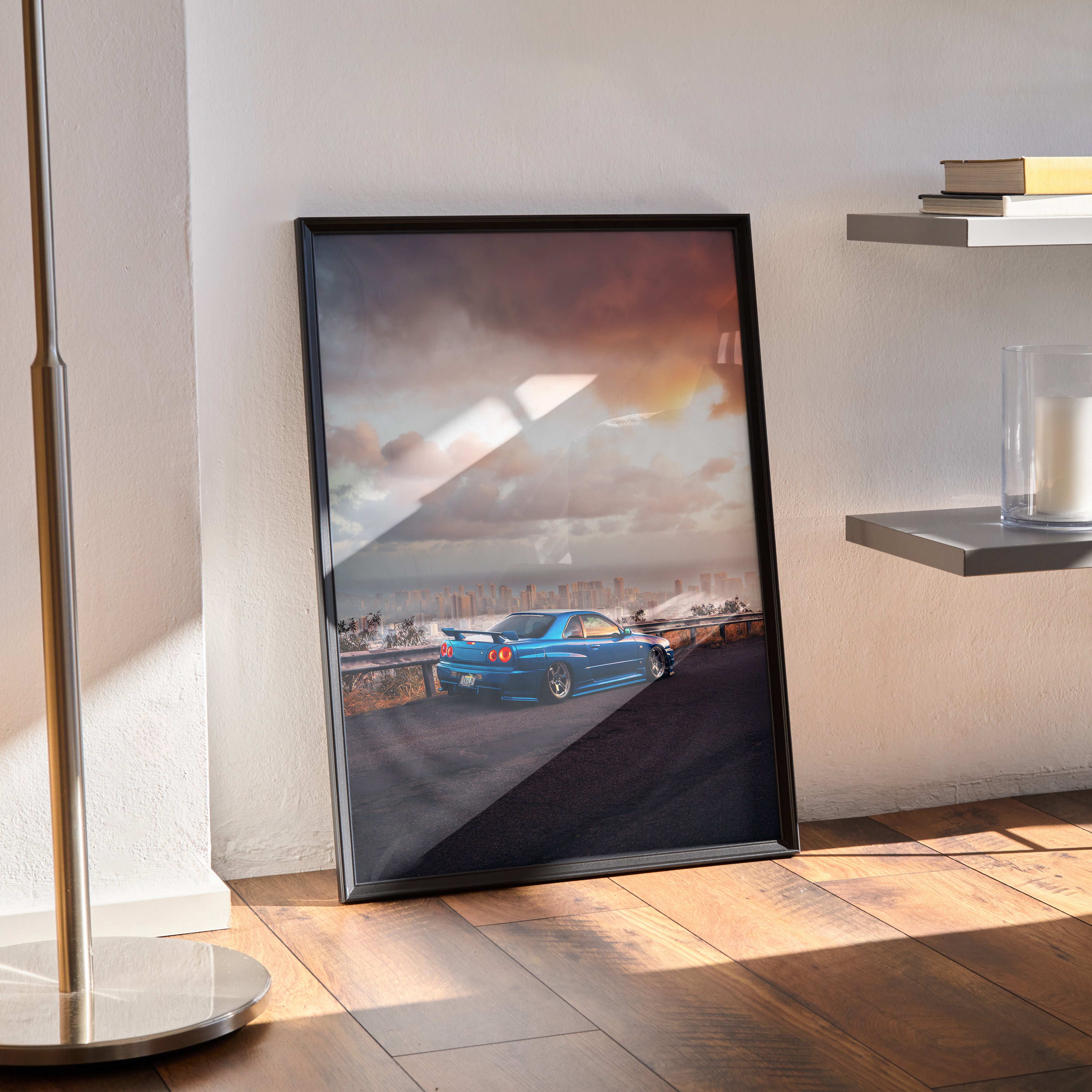 Nissan Skyline GTR R34 JDM car poster in black frame leaning on floor with sunset sky background, automotive wall art.
