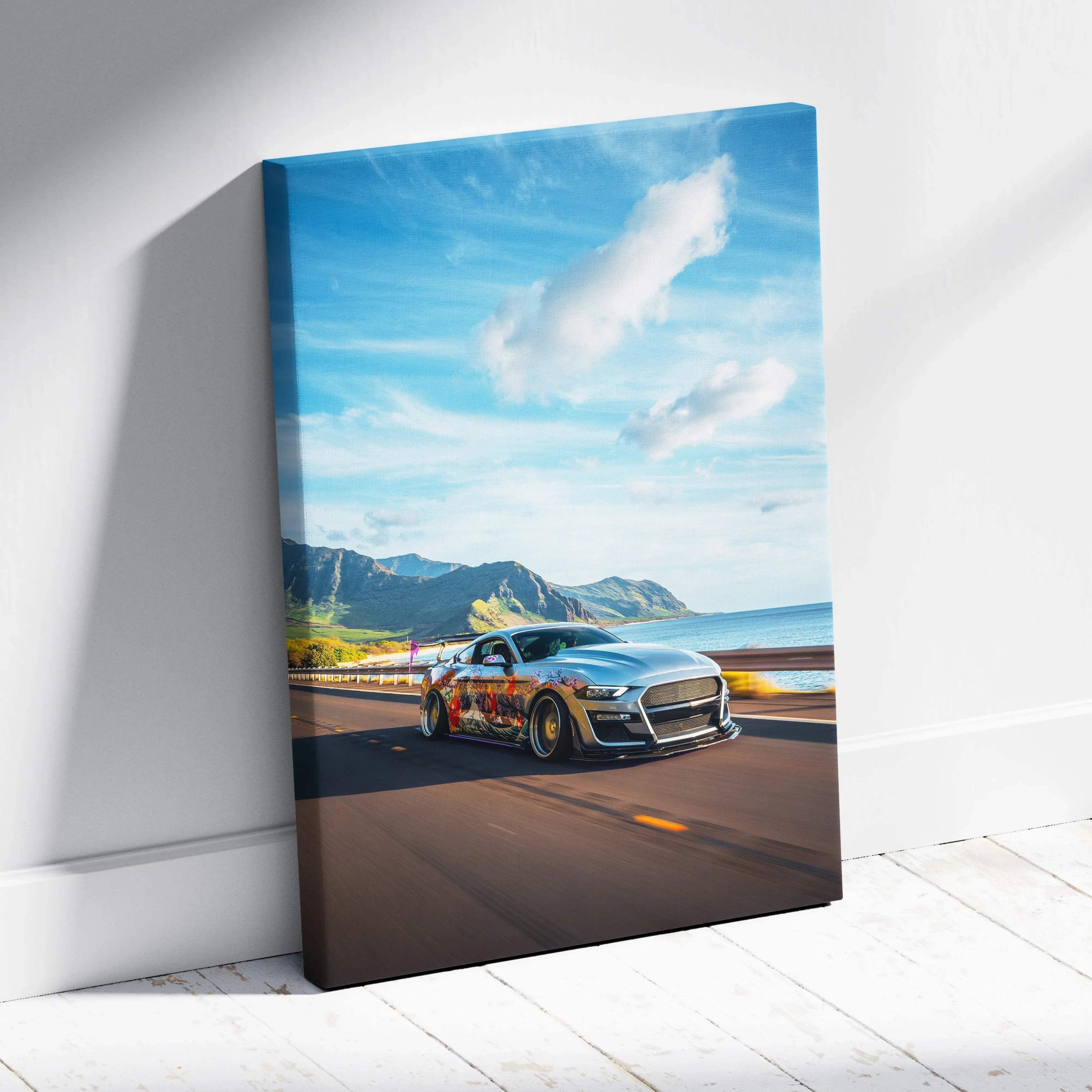 Vertical canvas wall art featuring a sleek black Ford Mustang S550 driving on a coastal road under a blue sky with clouds.