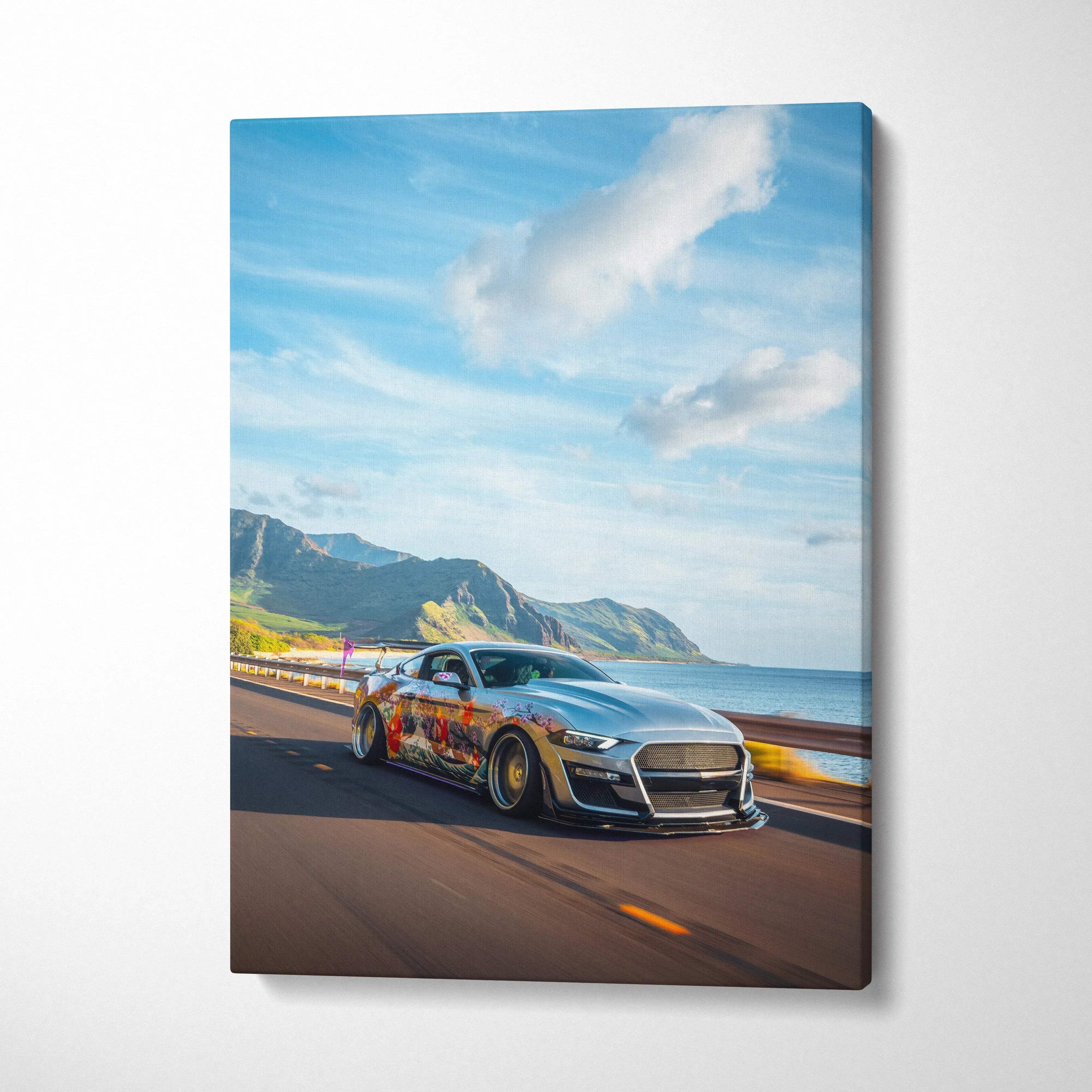 Vertical canvas art of a silver Ford Mustang S550 driving on coastal road with mountains and blue sky wall art.