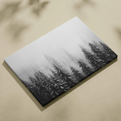 Canvas wall art featuring black and white digital print of snow-covered tree tops in foggy winter scene.