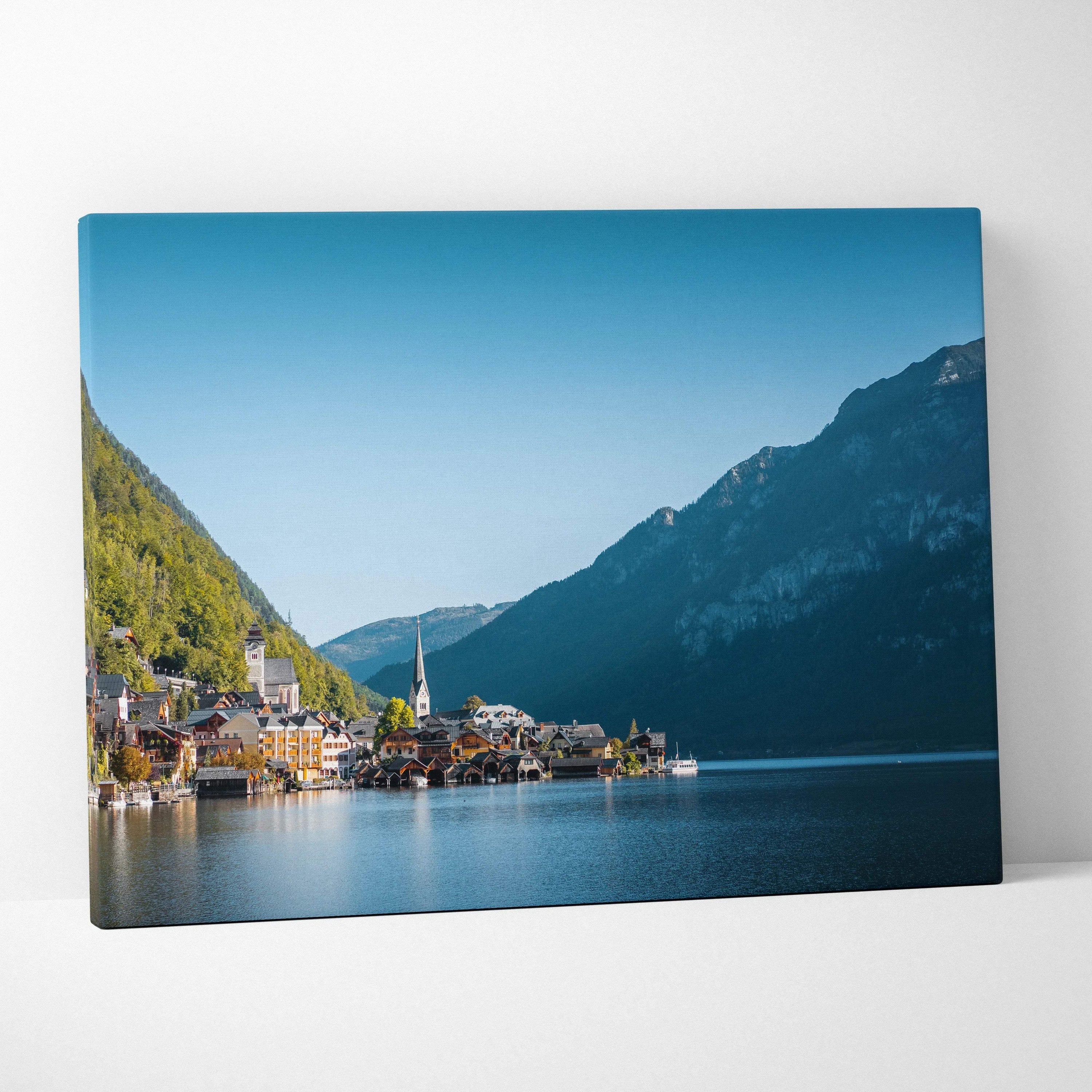 Canvas wall art featuring a serene lakeside village with colorful buildings, mountains, and clear blue sky.