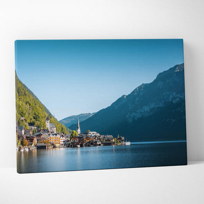 Canvas wall art featuring a serene lakeside village with colorful buildings, mountains, and clear blue sky.