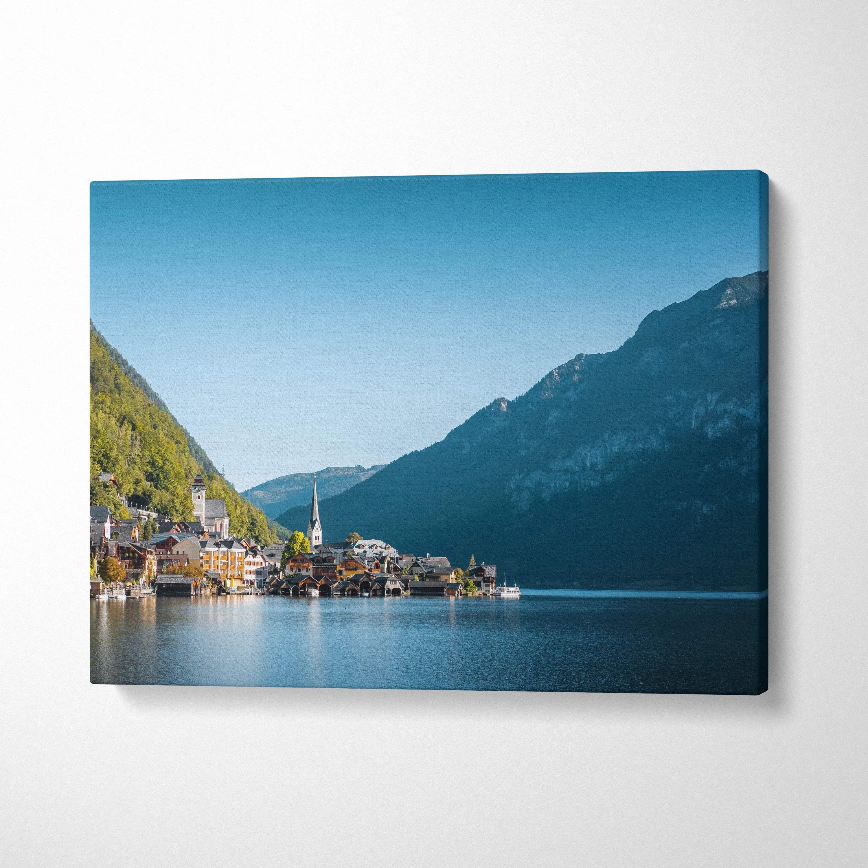 Canvas wall art featuring serene lakeside village with mountains under clear blue sky.