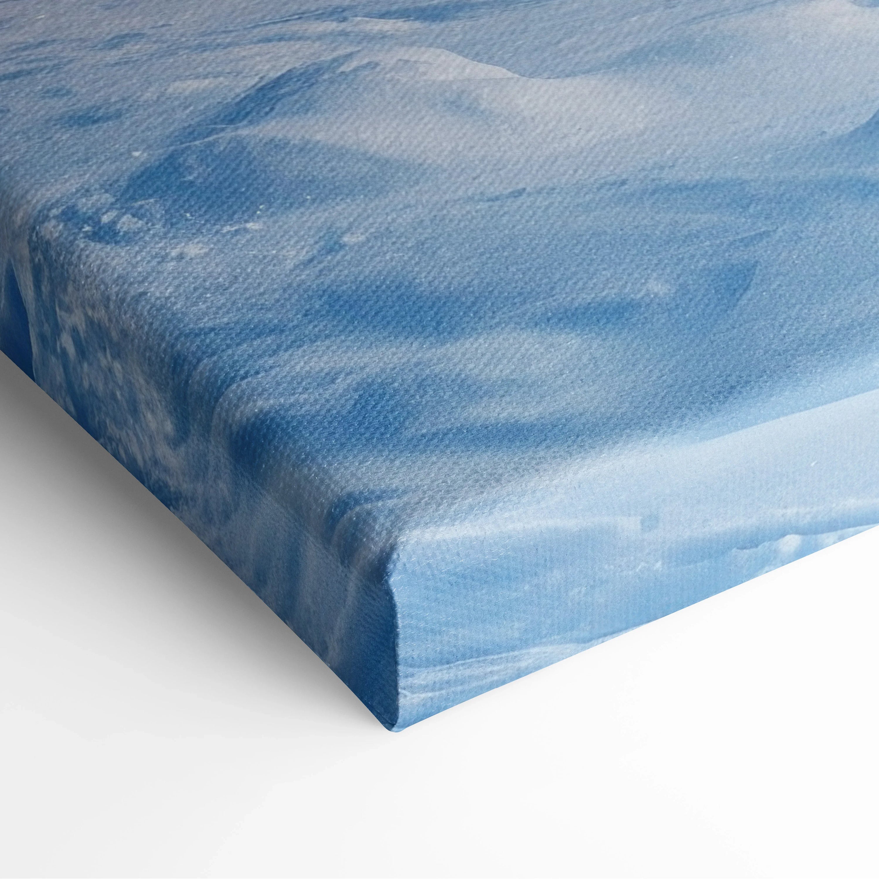 Close-up of canvas wall art featuring a snowy mountain peak with soft blue winter sky decor.
