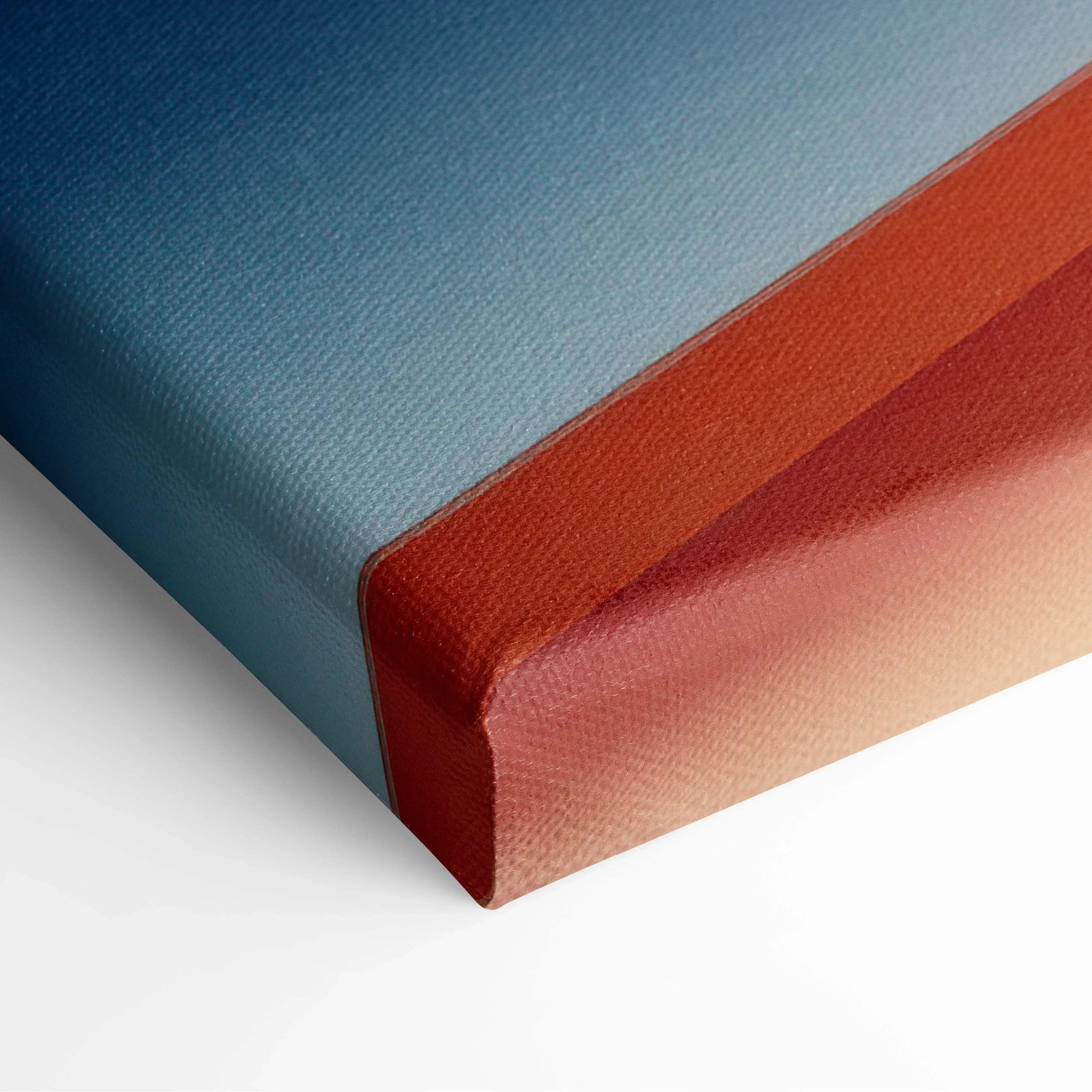 Corner close-up of canvas wall art with smooth gradient in blue and warm orange tones on textured fabric.