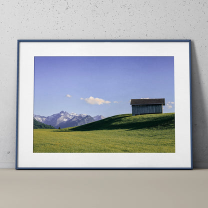 Majestic Mountain Nature Art Poster with cabin on grassy hill under blue sky wall art.