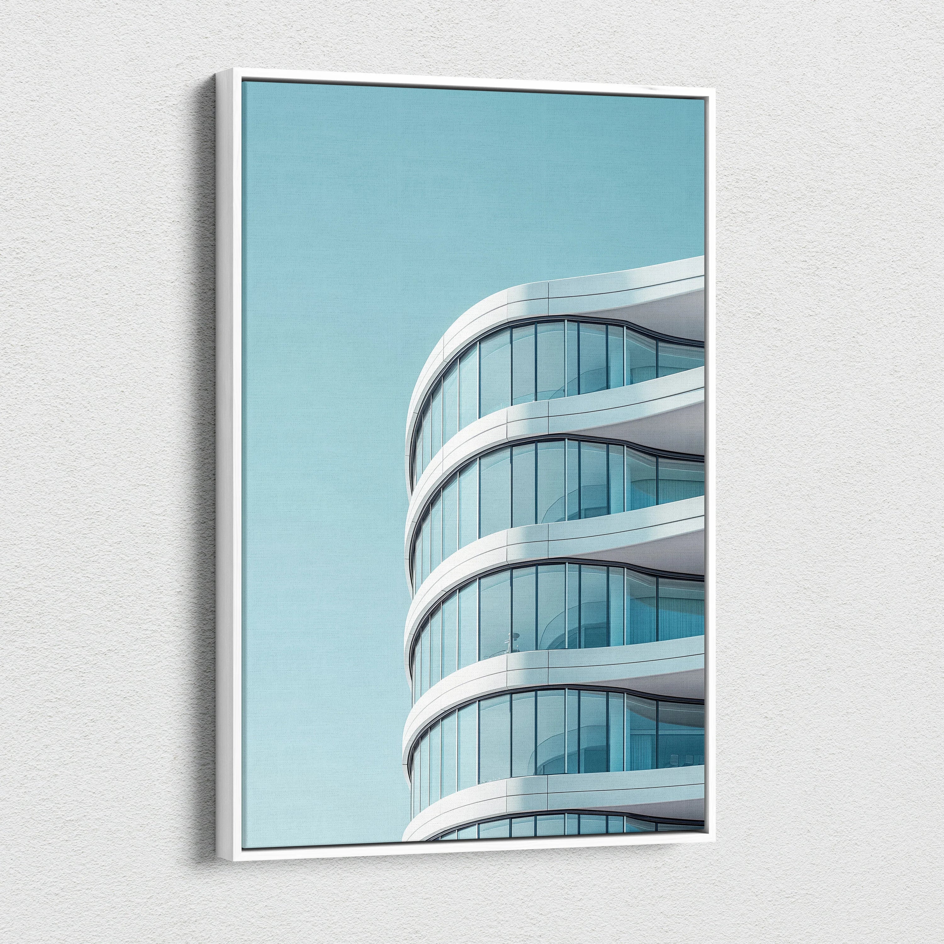 Modern curved glass building architecture on vertical canvas wall art with clear blue sky background.