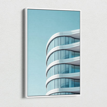 Modern curved glass building architecture on vertical canvas wall art with clear blue sky background.