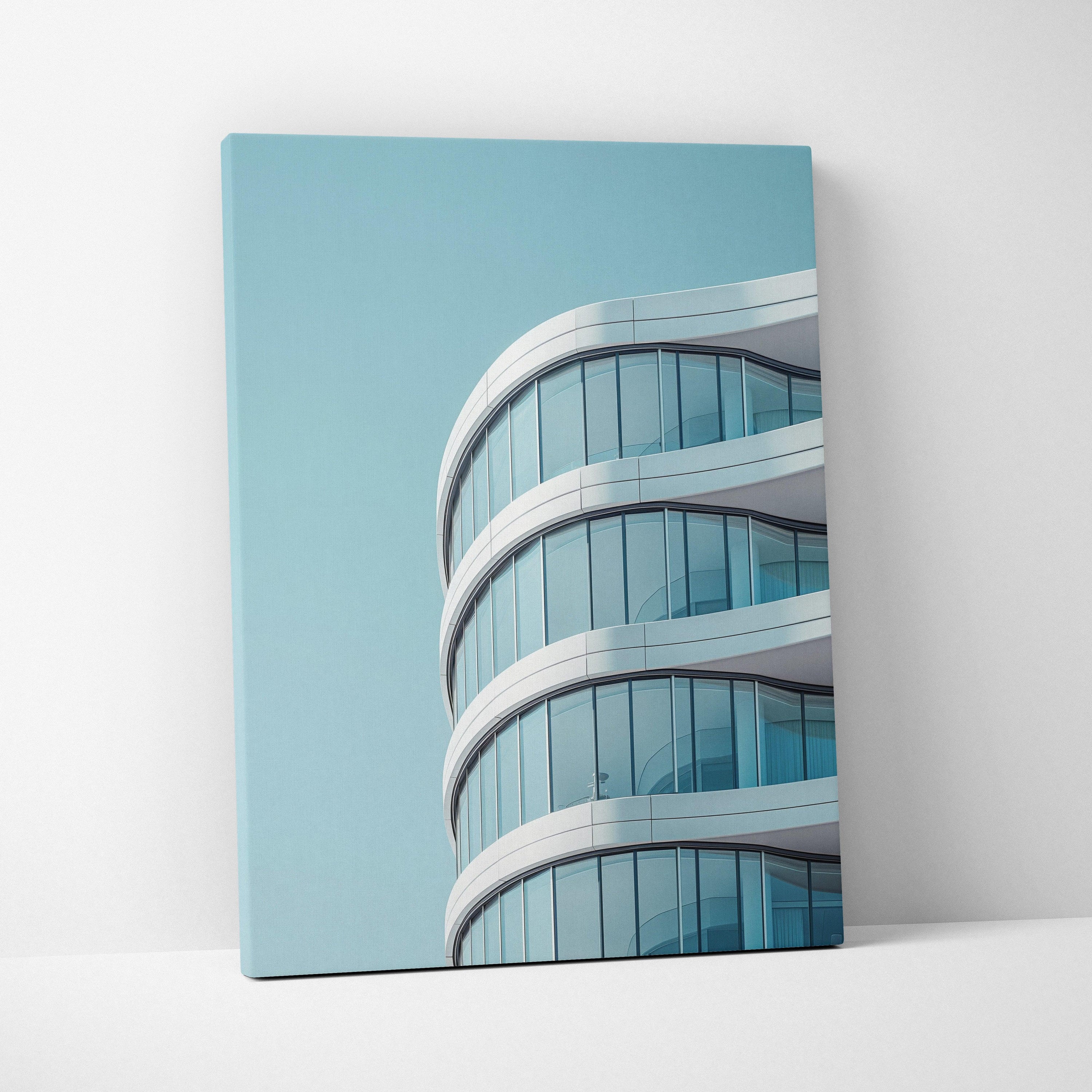 Modern curved glass building architectural canvas wall art with blue sky background.