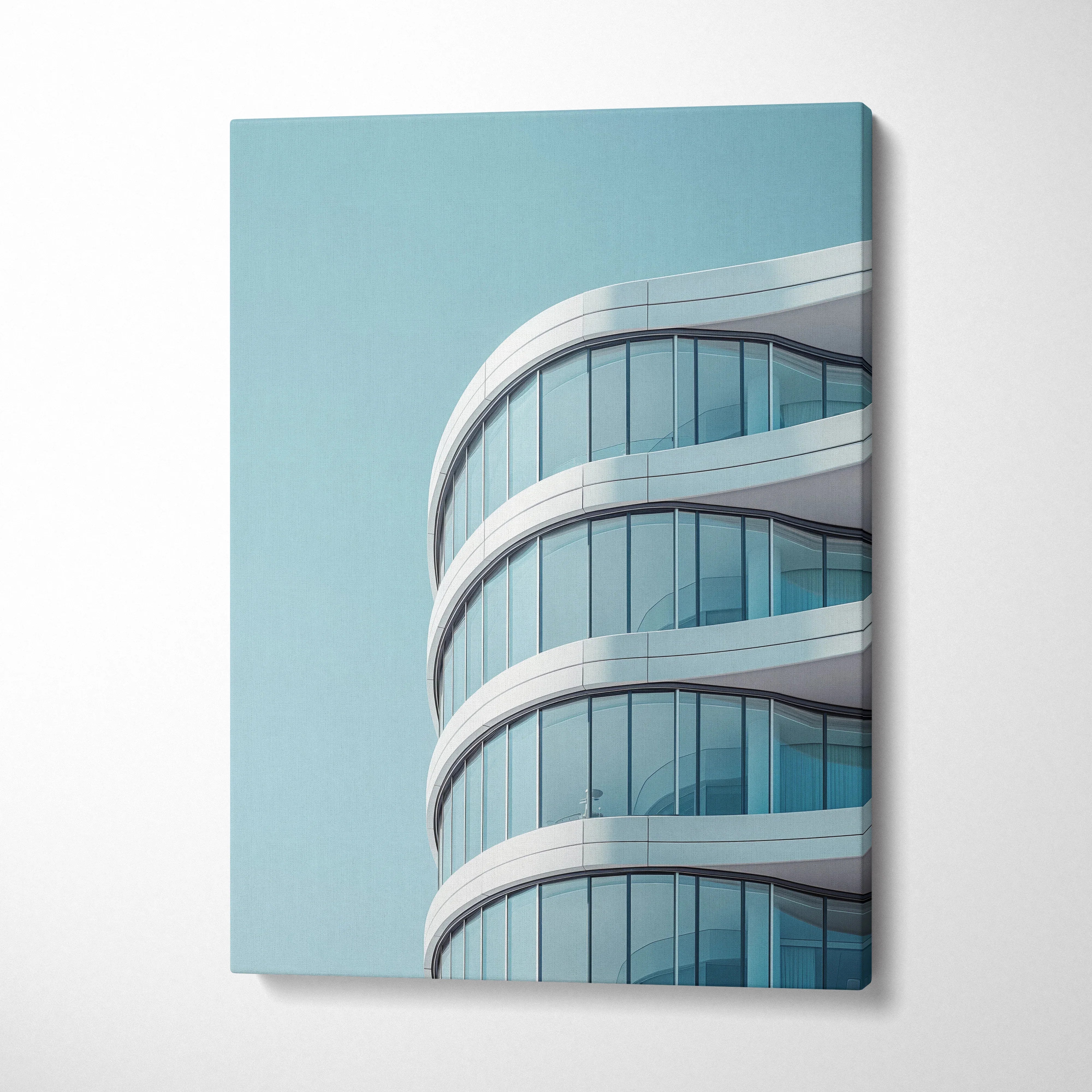 Modern curved glass building architecture on vertical canvas wall art with light blue sky background.
