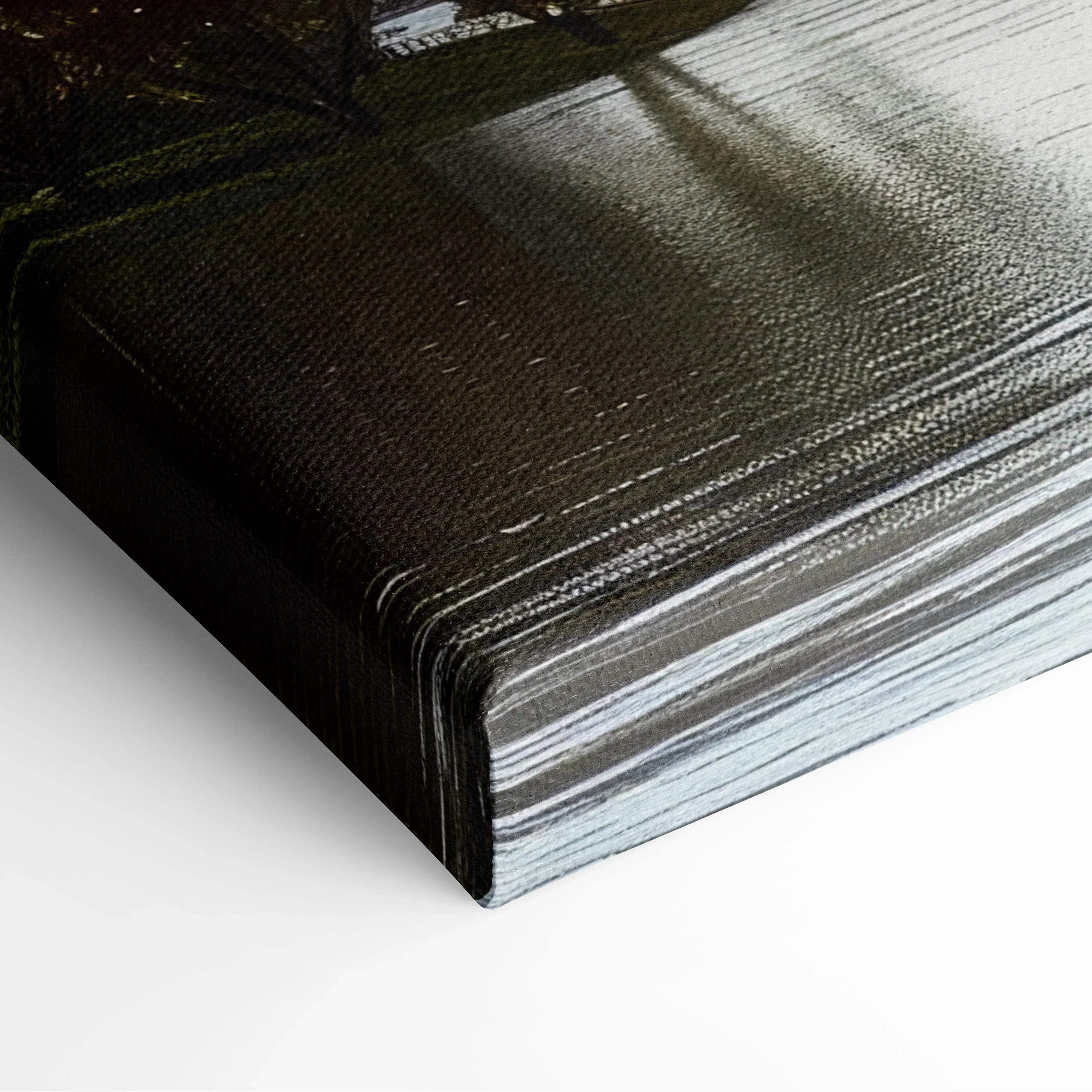Close-up of dark textured canvas art wrapped around wooden frame with subtle architectural shadows on surface.