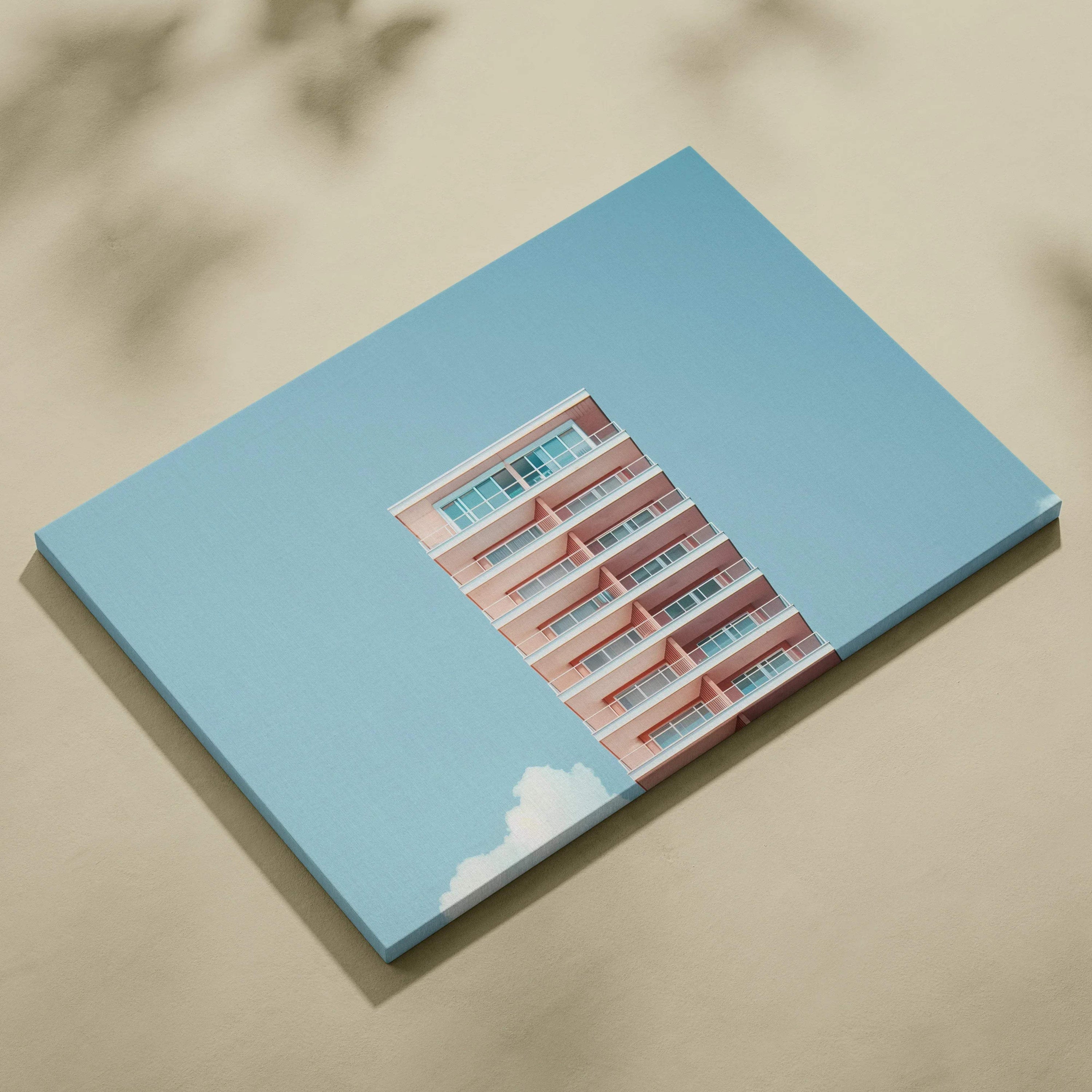 Canvas wall art featuring a pink modern building against a clear blue sky with white clouds, digital design.